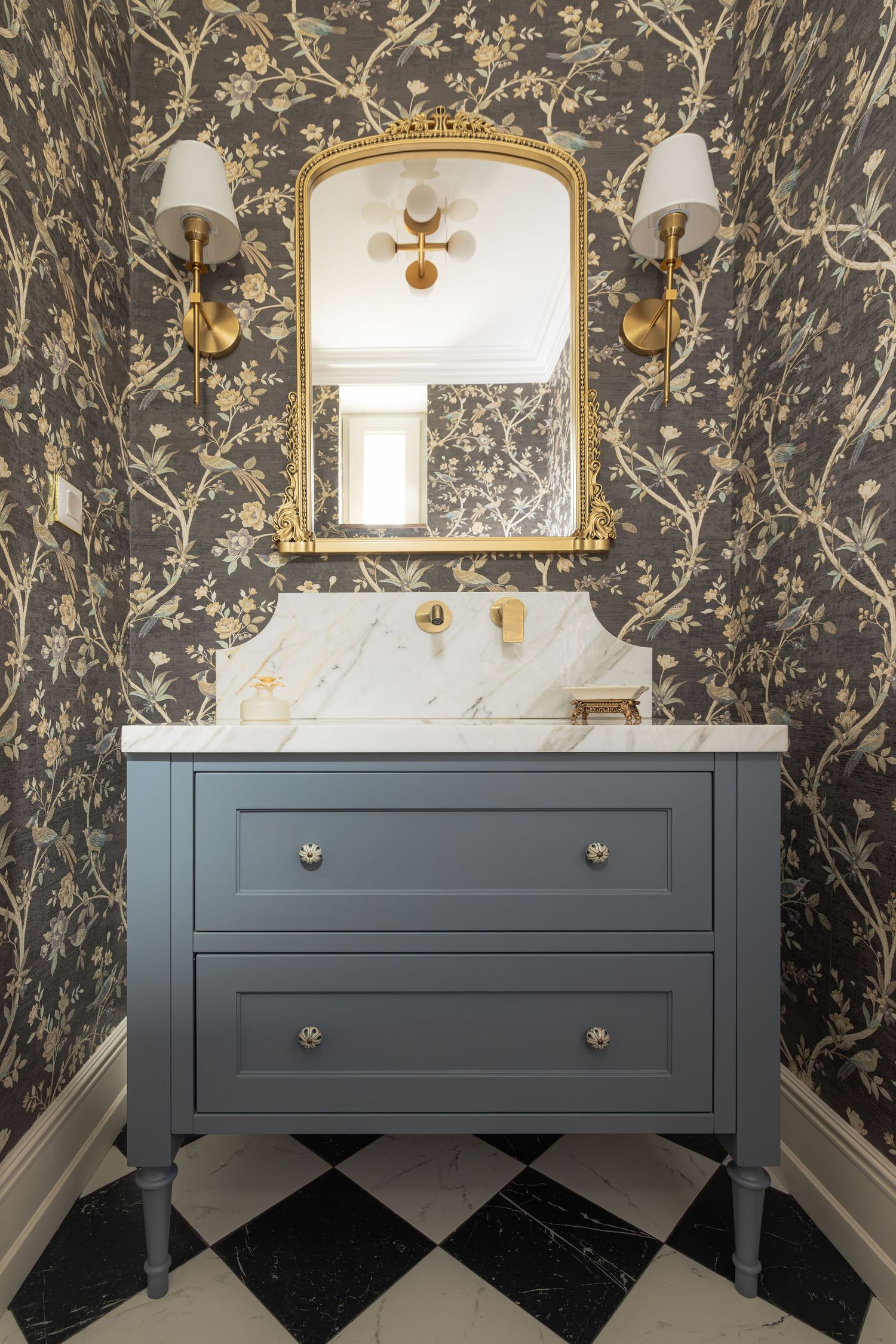 Dark floral wallpaper creates dramatic contrast with a gray vanity in an elegant powder room design by Vedrana Markovic,