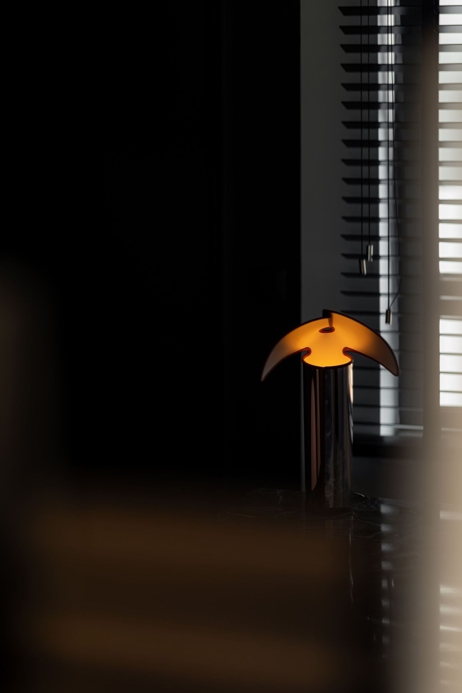 A series of images showing a glowing orange pendant lamp against a dark background with window blinds casting shadows.