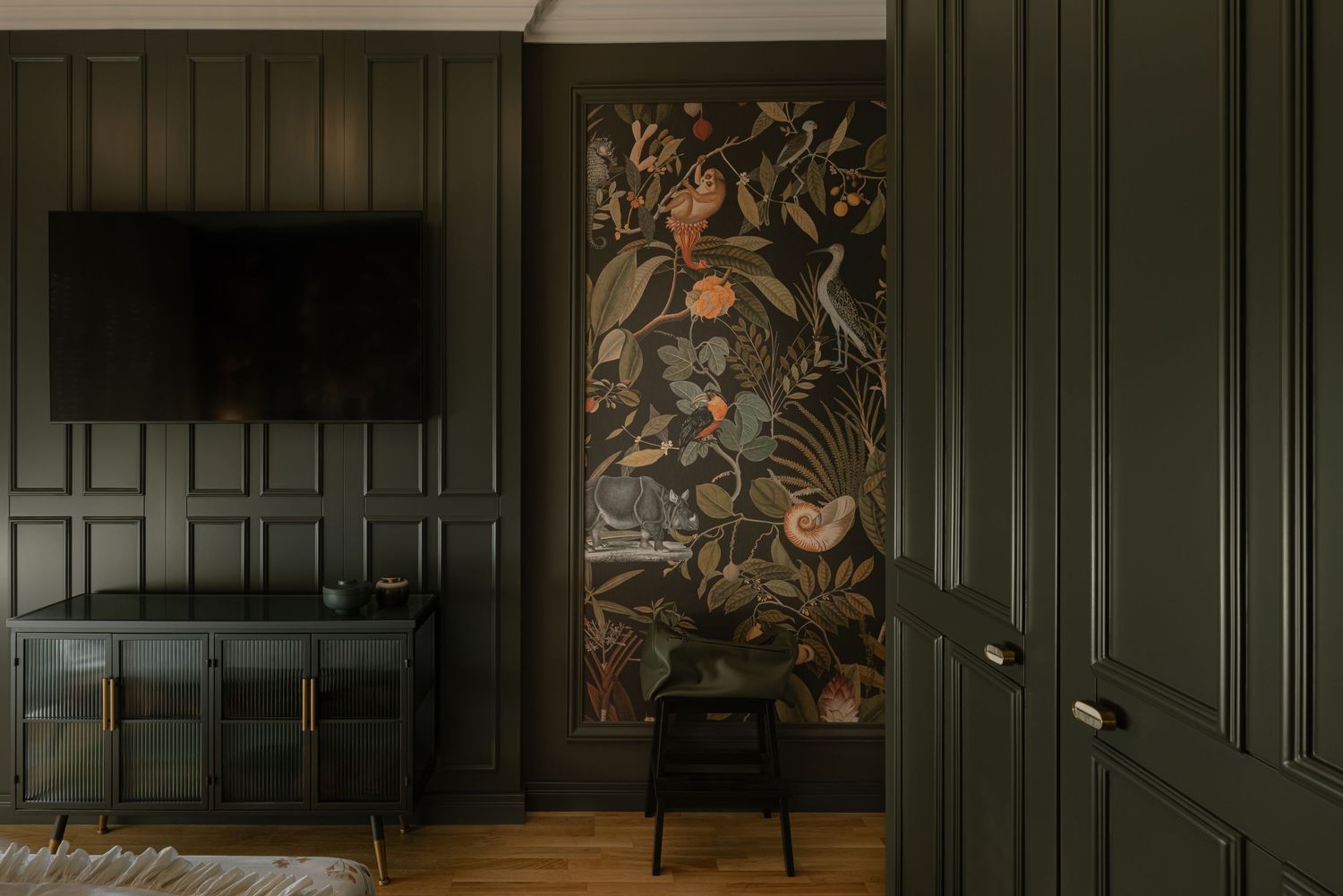 Dark green paneled walls create a moody atmosphere in a vintage-style interior space with ornate floral artwork by Vedrana Markovic.