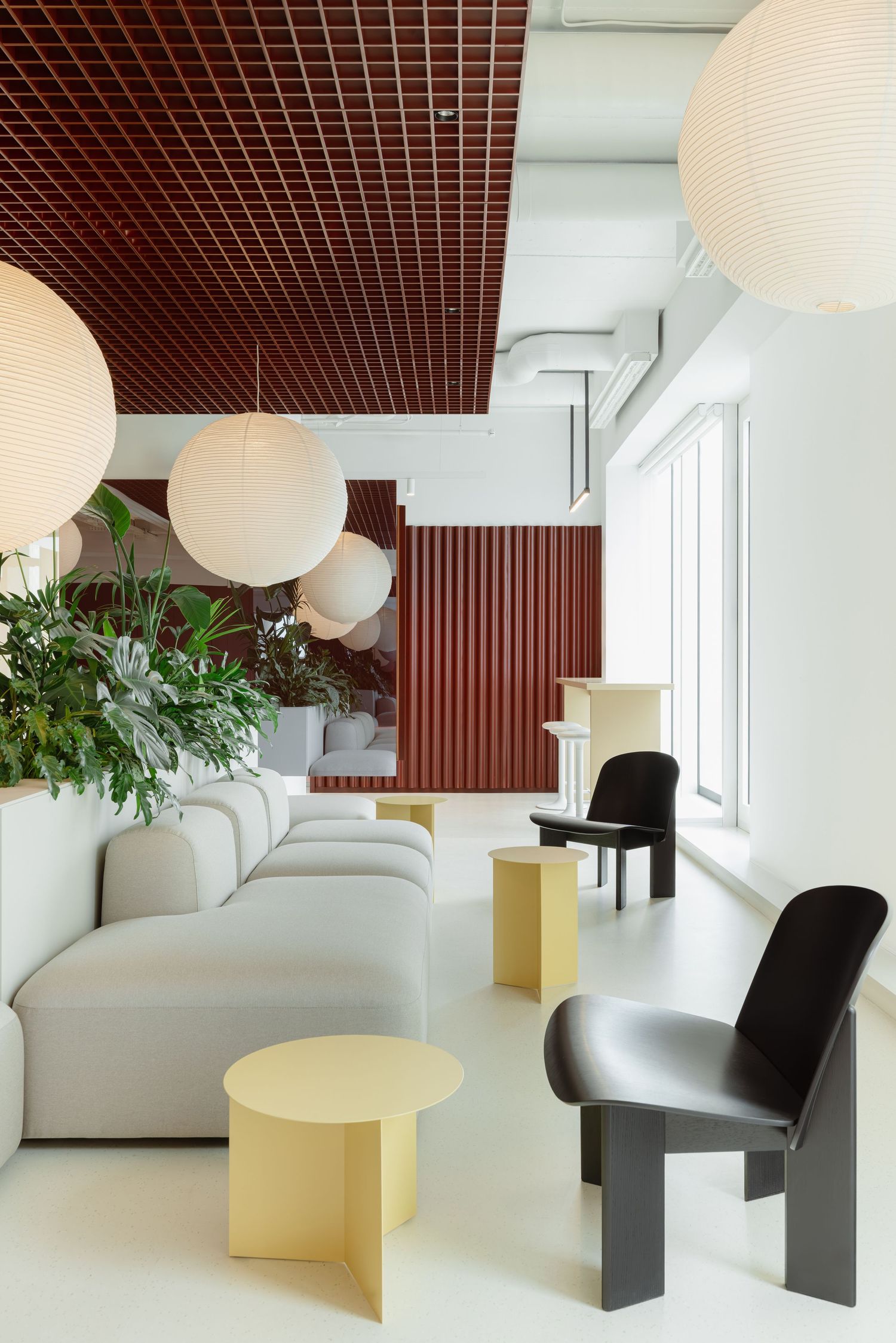 Modern lounge with white sofas, yellow tables, black chairs, and globe pendant lights.
