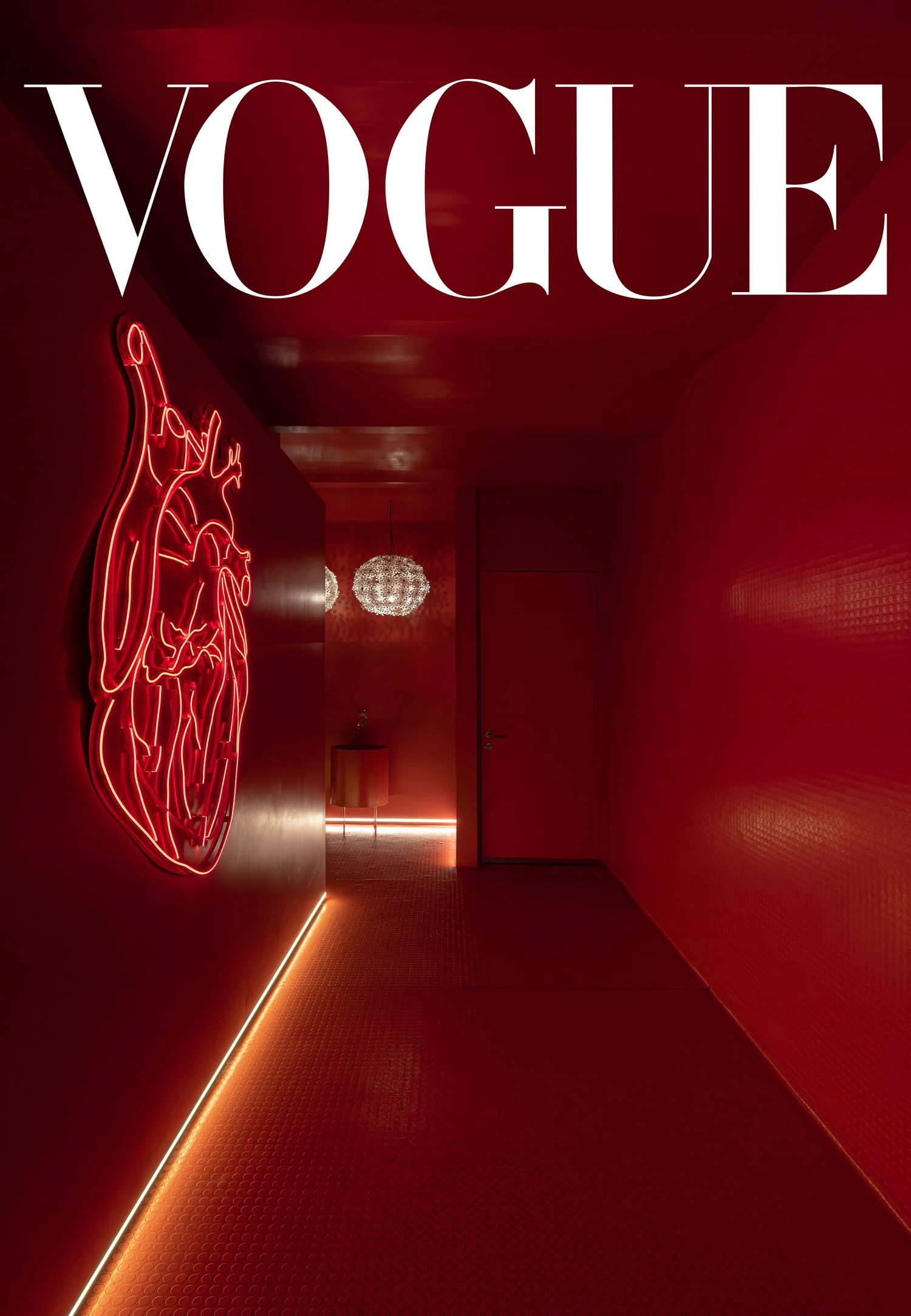 Glowing red neon VOGUE text signs mounted on dark walls in a dimly lit hallway.