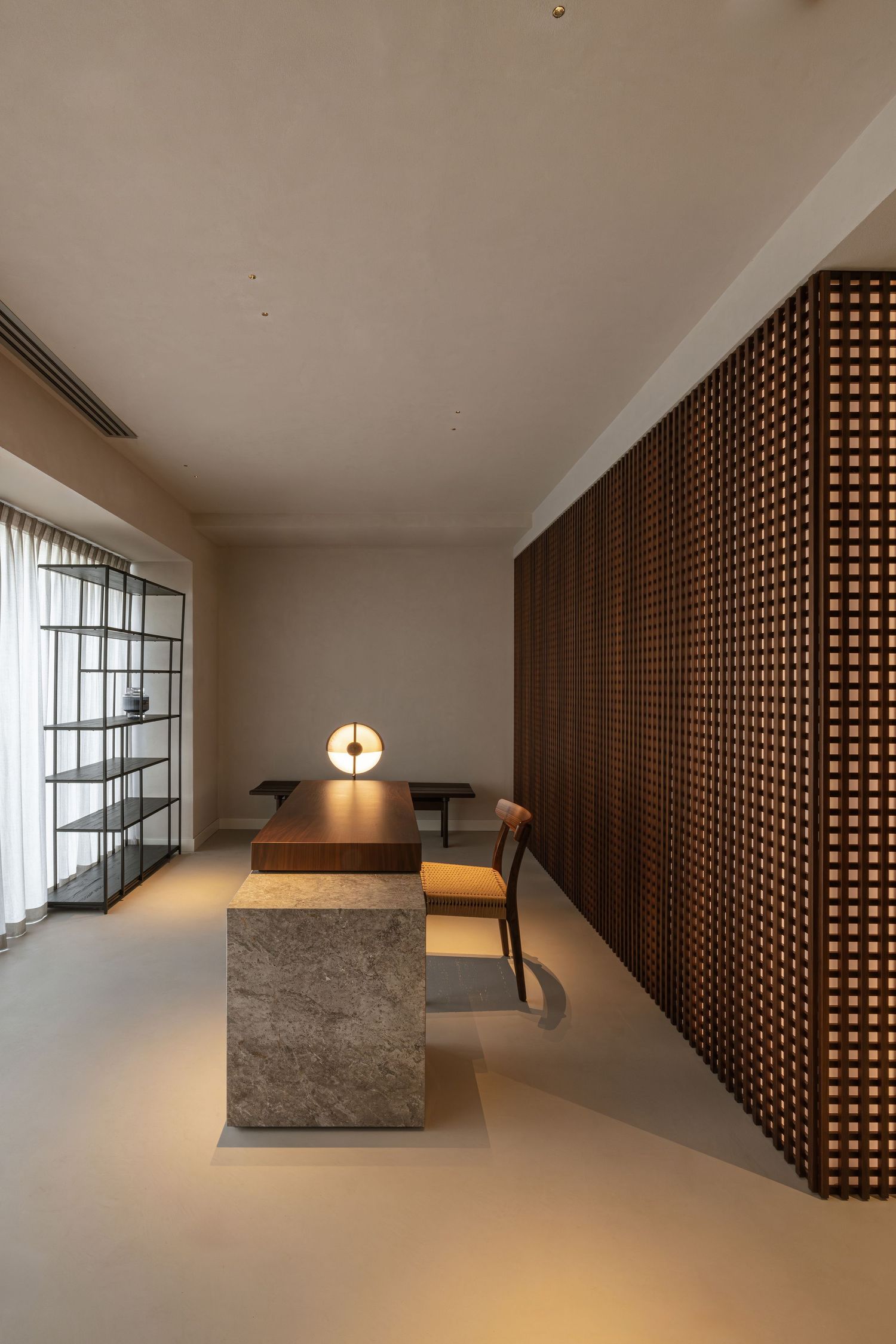 Interior design featuring wooden lattice screens, concrete walls, and minimalist lighting in a sleek architectural space by Studio Fluid.