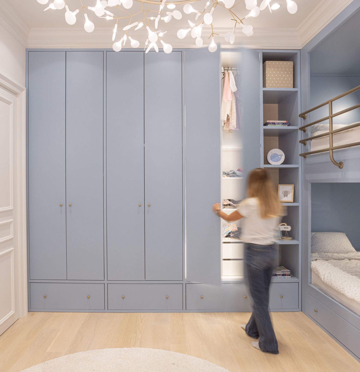 Light blue built-in cabinets with gold hardware create elegant storage in a modern mudroom space by Stasa Radmilovic, Dello Studio.