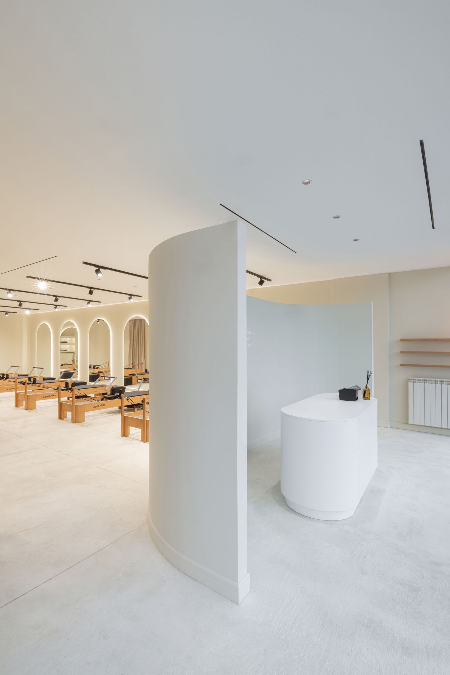 Elia Pilates Center interior with curved walls, track lighting, and seamless flooring in a contemporary design by Sonja Rajic.