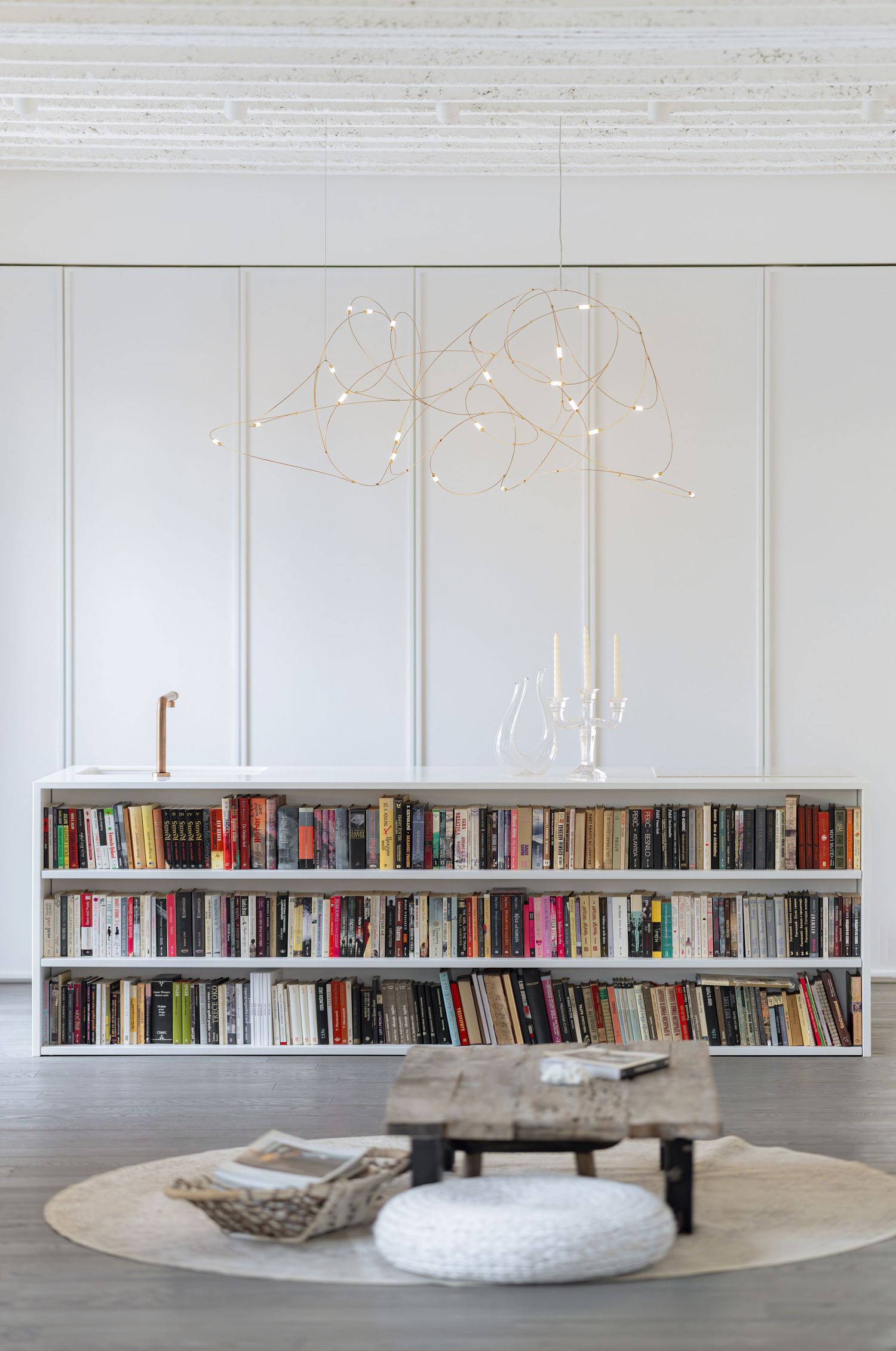 Modern interior design featuring white bookshelves with illuminated star-shaped lights and a curved white table centerpiece.