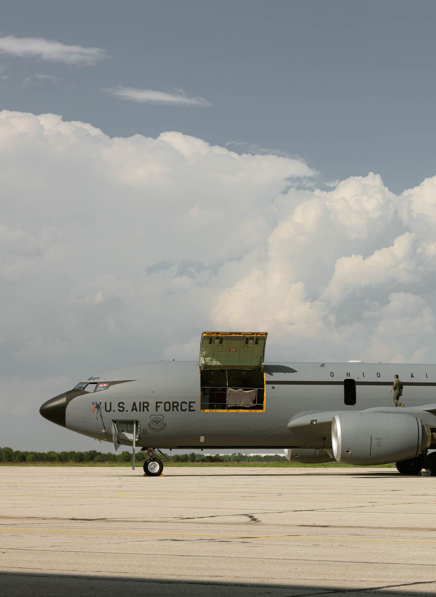 Close-up view of a U.S. Air Force aircraft nose section and fuselage parked on a sunny tarmac with clouds in the sky.