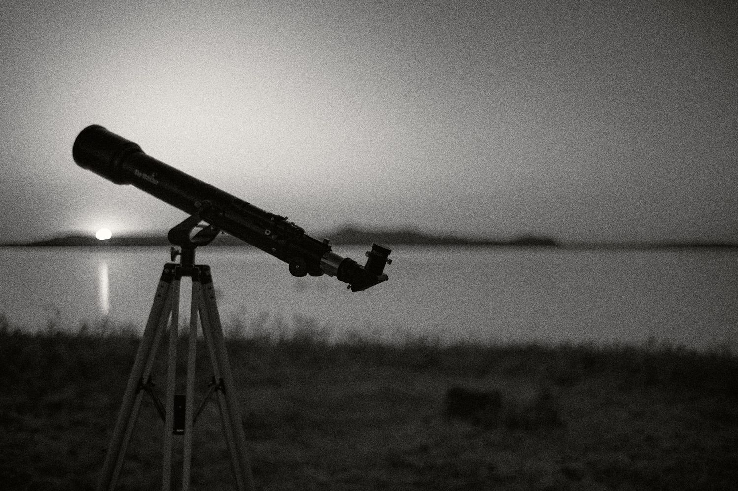 A series of black and white landscape photographs featuring telescopes and silhouettes against moody skies.