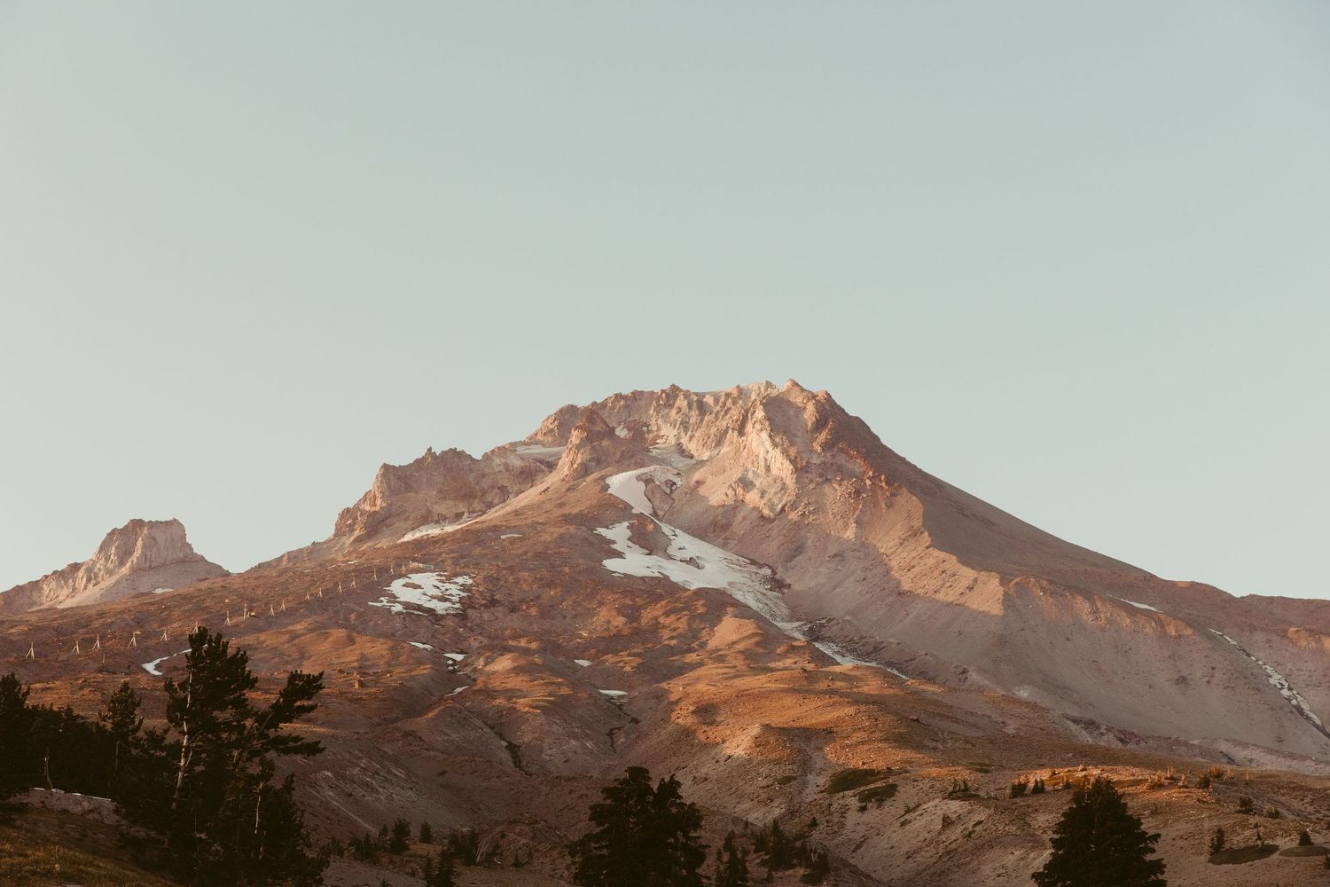 Mount Hood in Oregon glows with warm alpenglow at sunset as viewed from multiple angles along the mountain range.