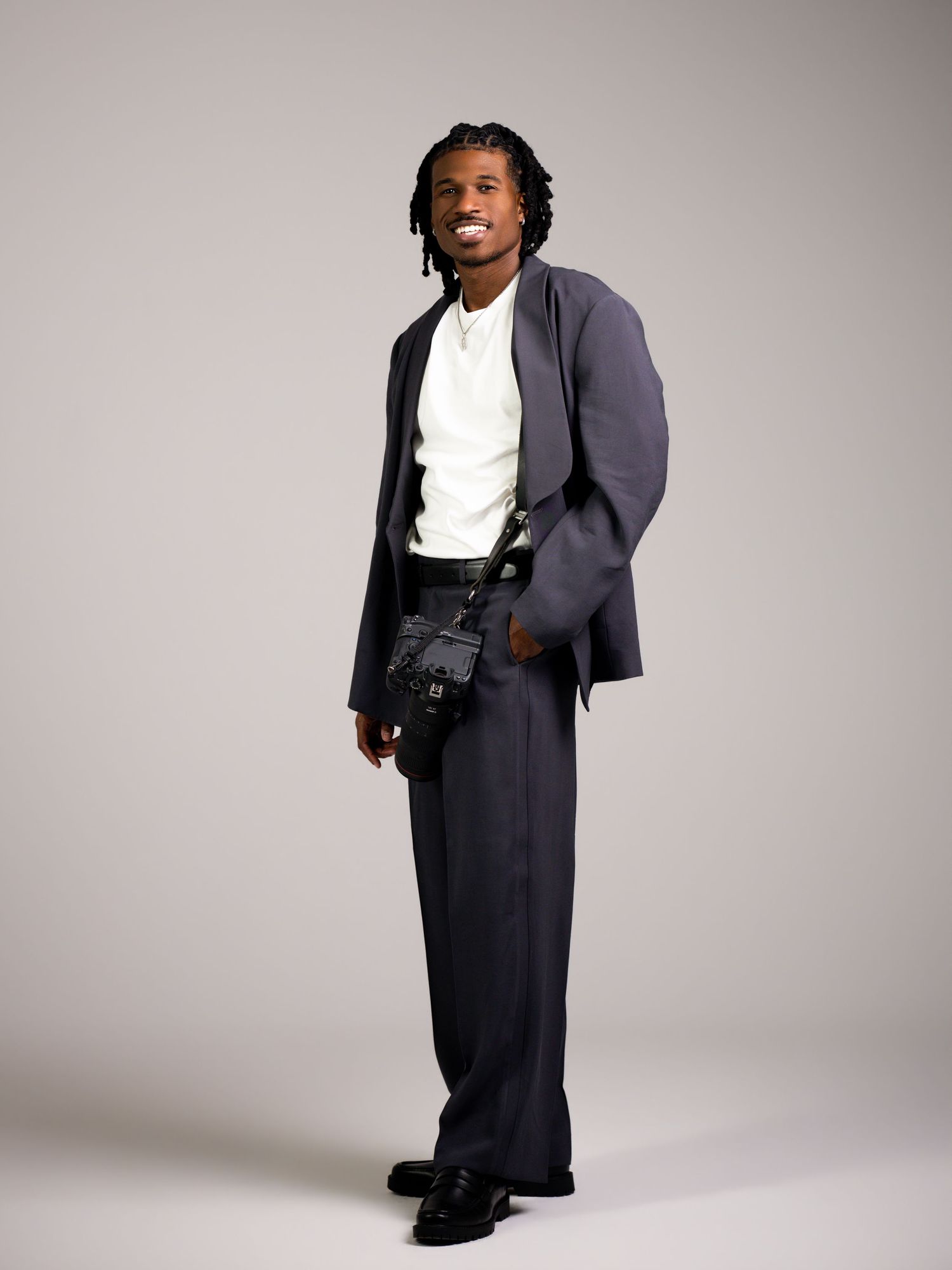 A person in a dark blazer and white shirt poses in various stances against a light gray studio backdrop.