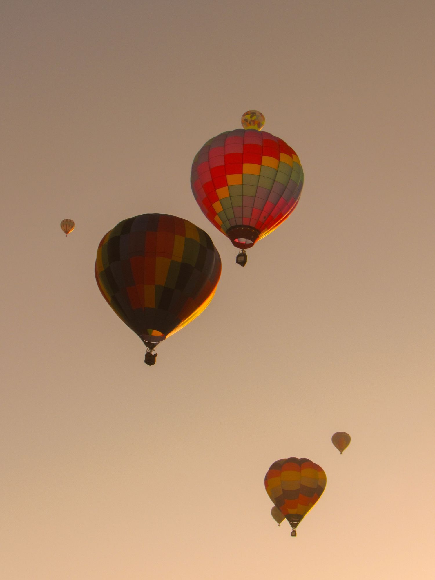 Hot air balloons float gracefully against a warm sunset sky creating a magical silhouette display.