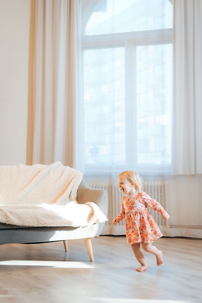 1-vuotias tyttö juoksee iloisesti aurinkoisessa valokuvaussudiossa.