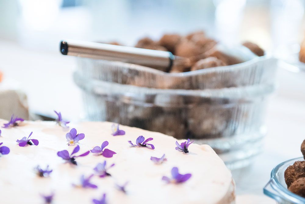 Yksityiskohtakuva valkoisesta kakusta, joka on koristeltu useilla violeteilla orvokin kukilla.