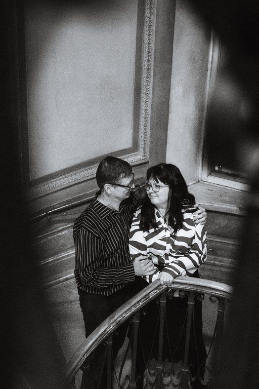 Mustavalkoinen kontrasinen kuva, jossa 50-vuotias pariskunta katsoo toisiaan portaikossa.