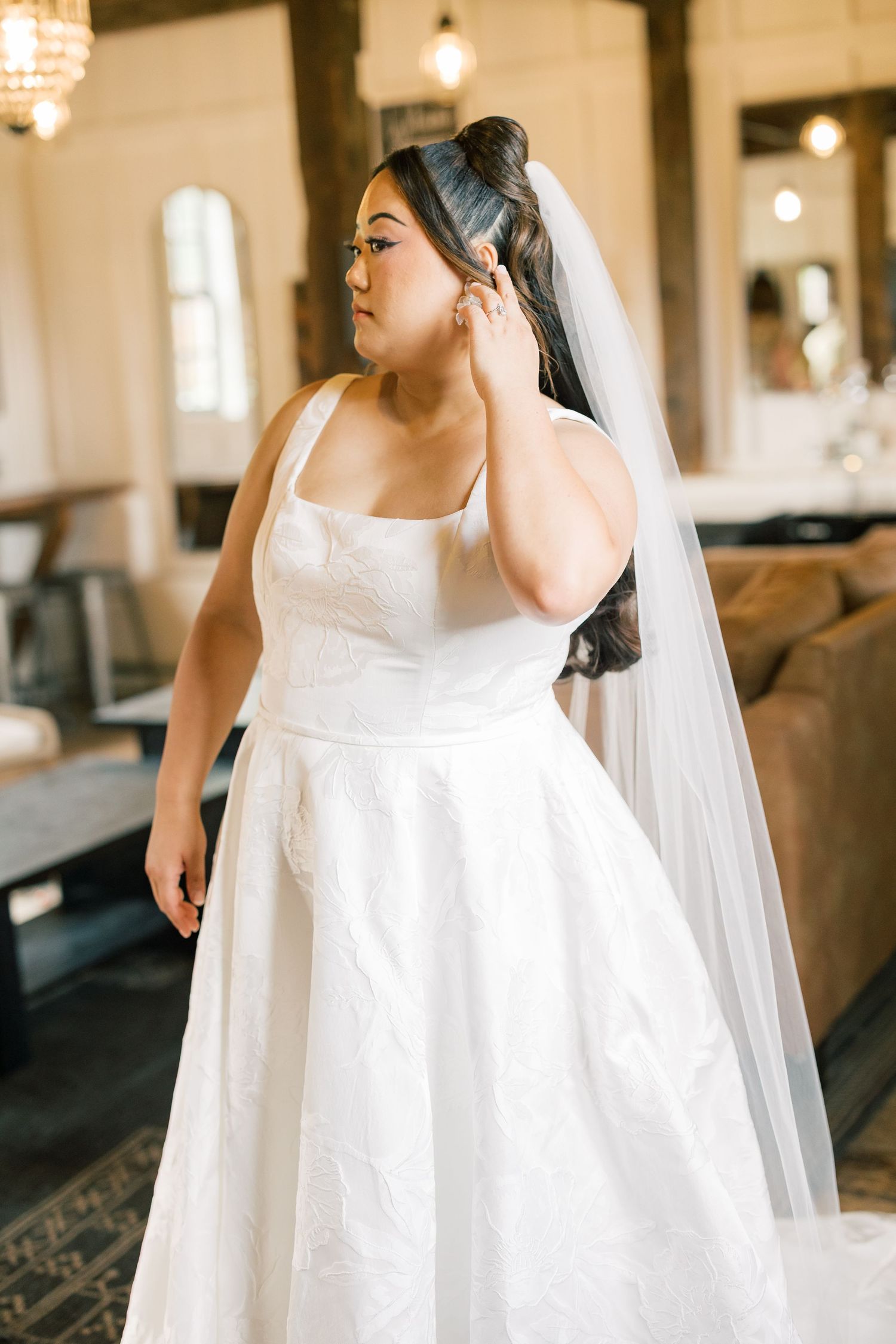 Elegant white wedding gown with flowing veil captured in an indoor venue.