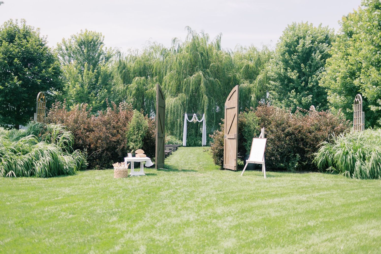 Scenic outdoor wedding venue with green lawn and trees in background.