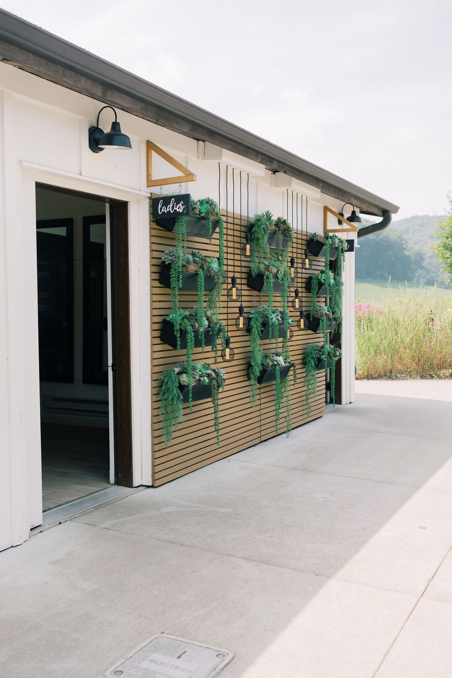 Modern garage exterior with wooden slat wall and hanging greenery decorations.