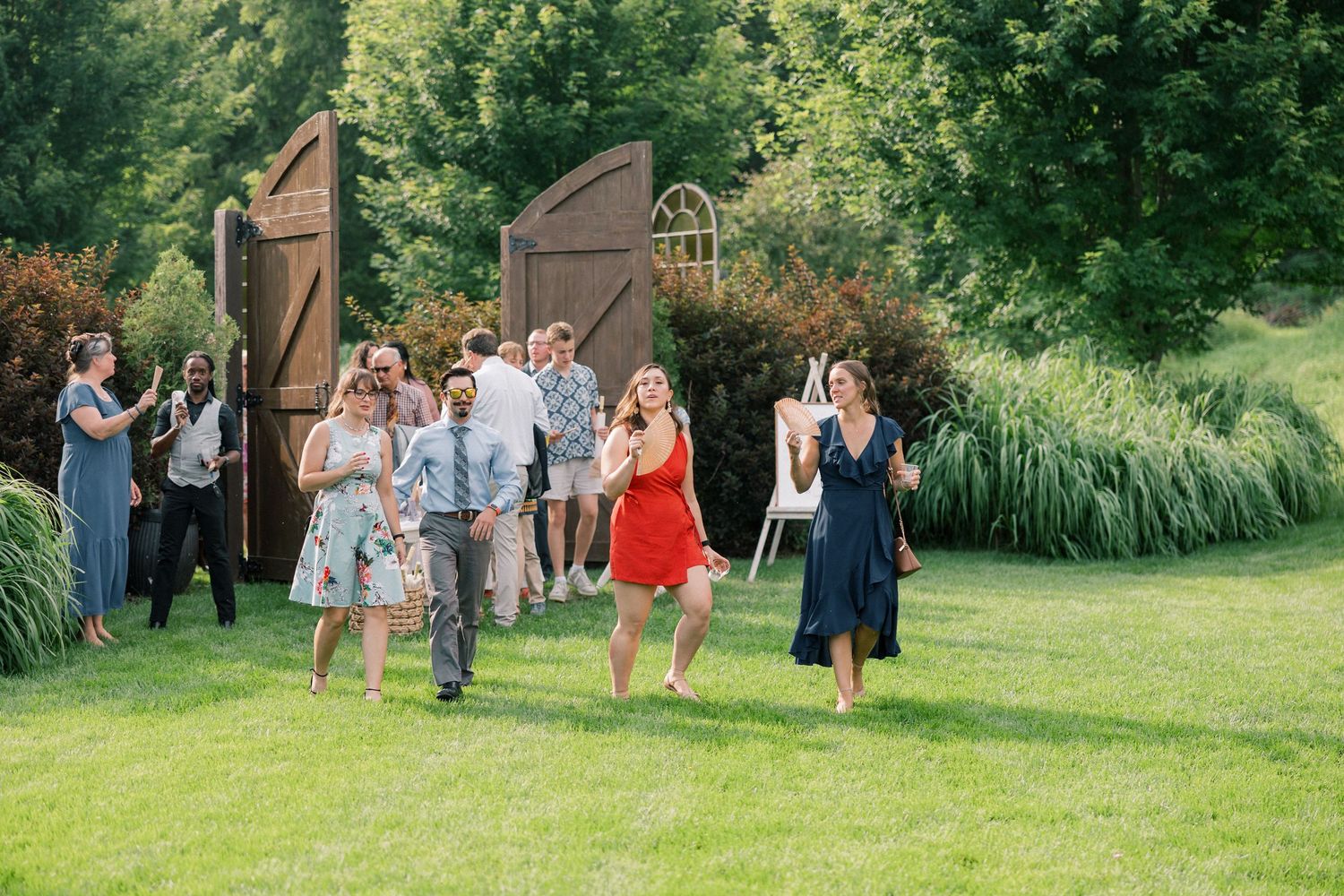 Wedding guests mingling on lawn during outdoor summer reception.