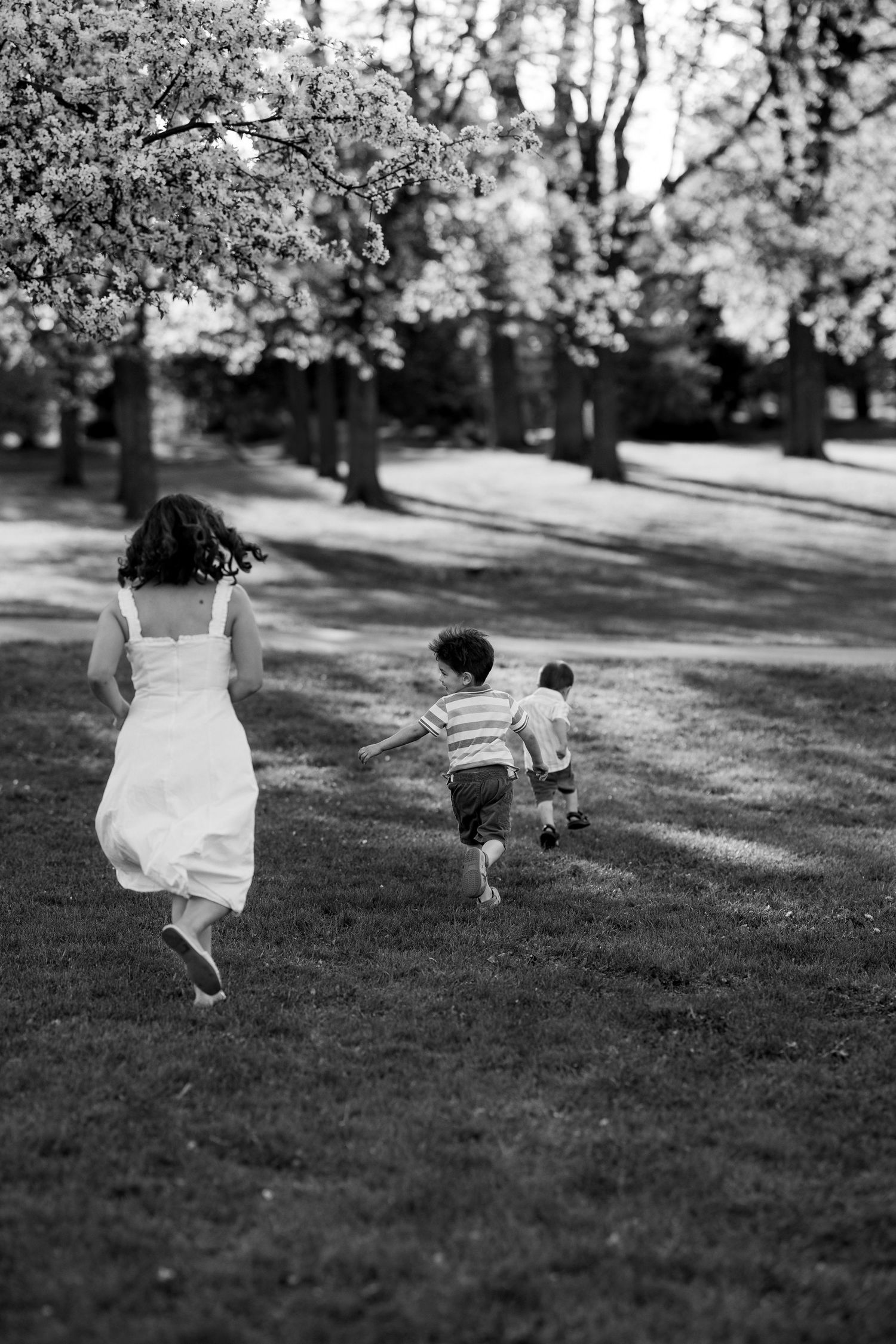 Black and white sequence of two people running and jumping playfully across a grassy hill on a sunny day.
