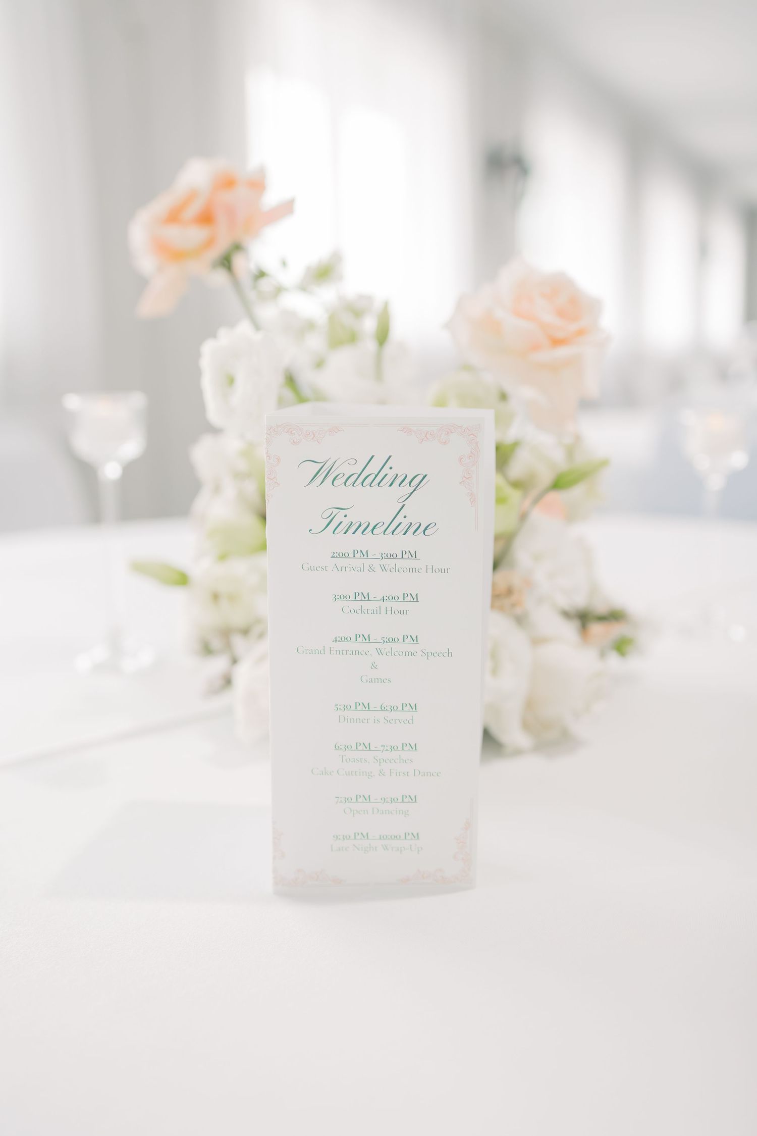 Elegant wedding timeline cards with floral decorations and soft blush tones on a white table.