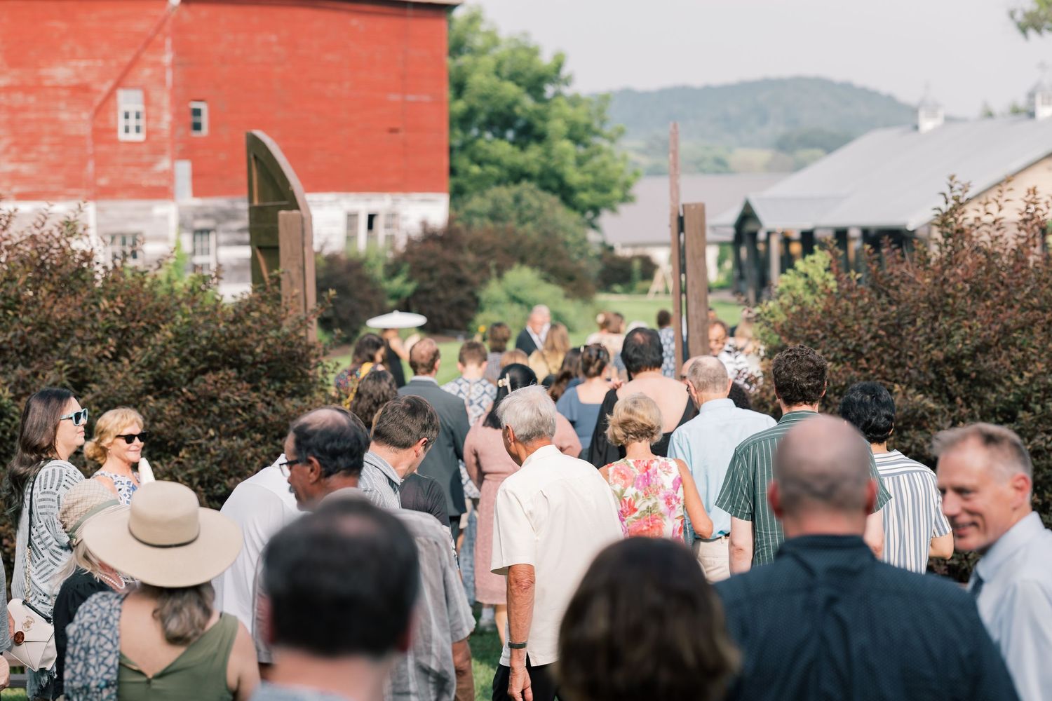 Large crowd of wedding guests mingling outside with red brick buildings in the background.