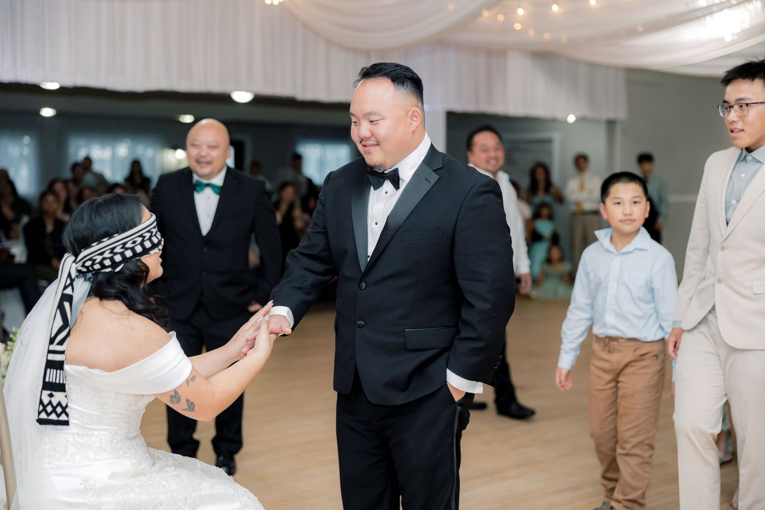 Wedding guests dancing and celebrating together on a decorated dance floor under white fabric draping.