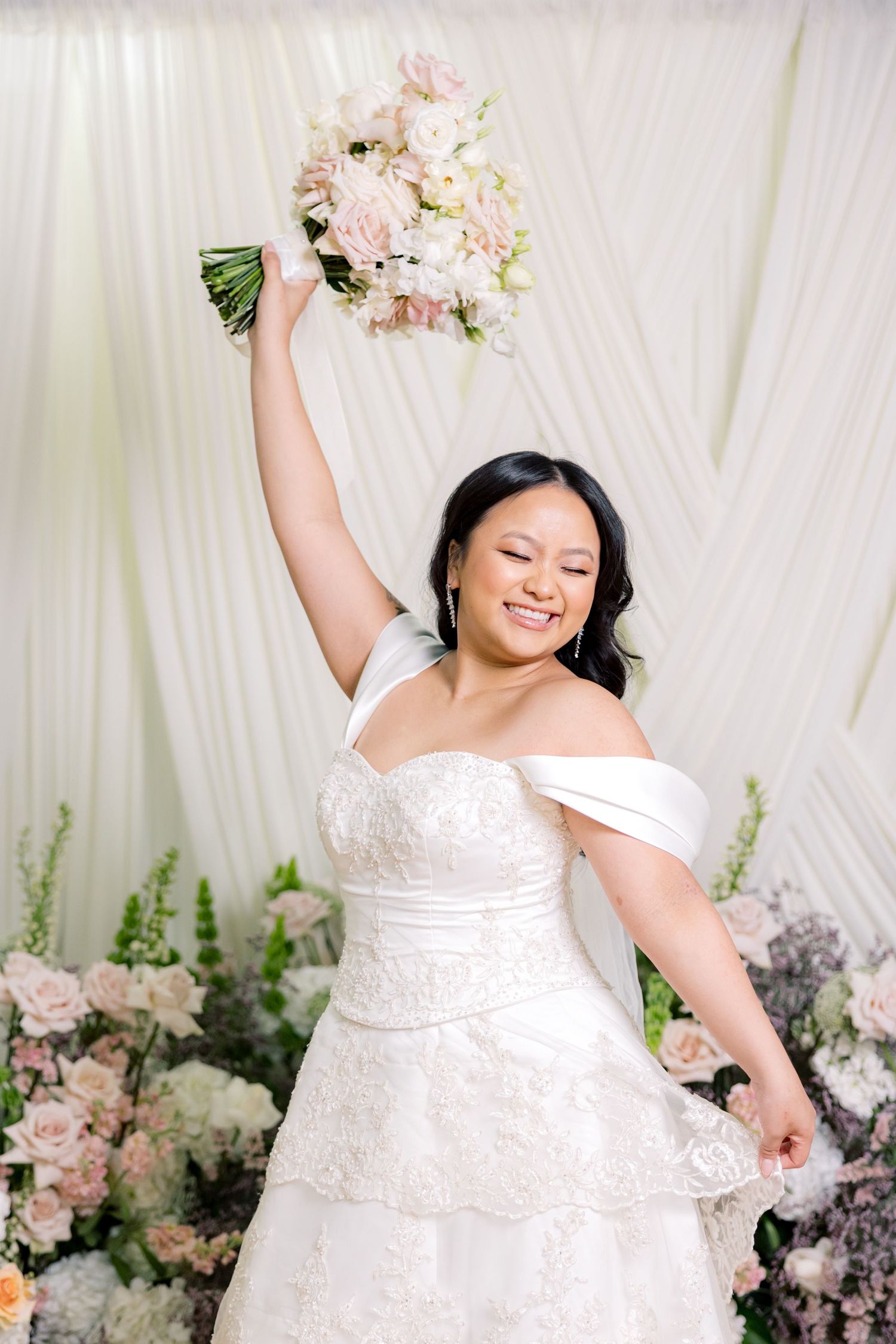A joyful moment captured in a wedding scene with a white dress and pink floral bouquet.
