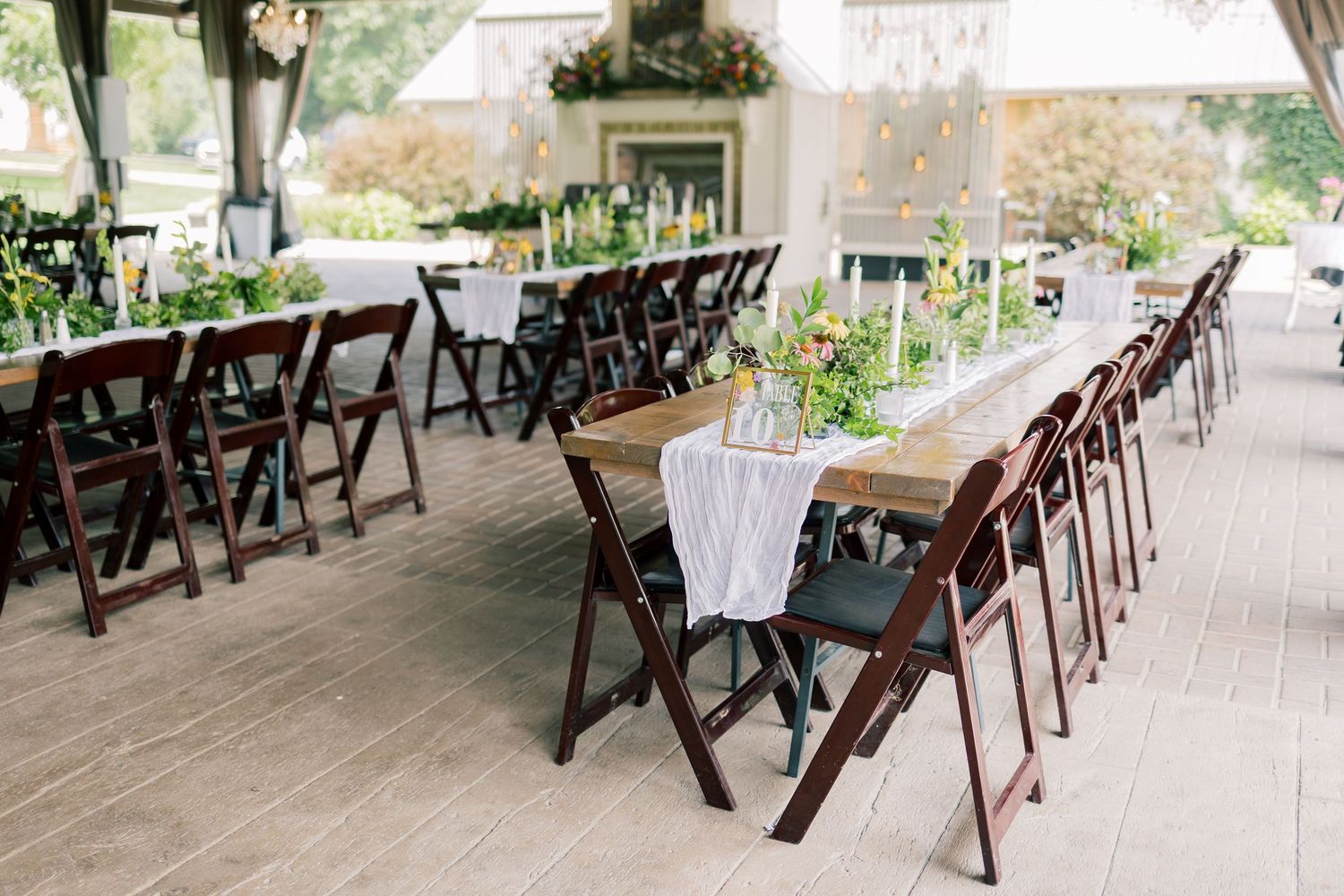 Outdoor wedding venue setup with dark wooden chairs and covered patio area.