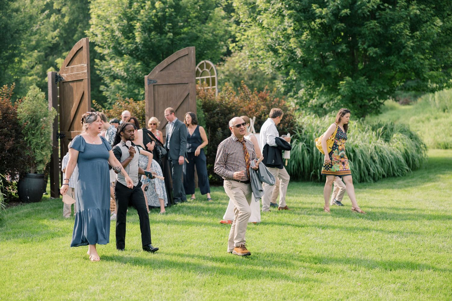 Wedding guests socializing on a green lawn during an outdoor summer reception.