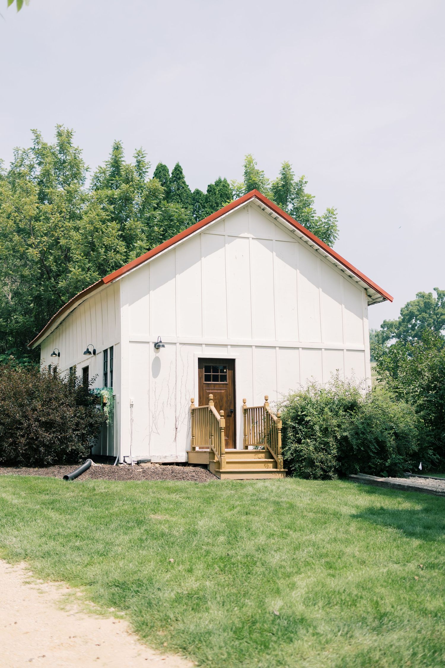 White barn-style wedding venue with red trim photographed from different angles.