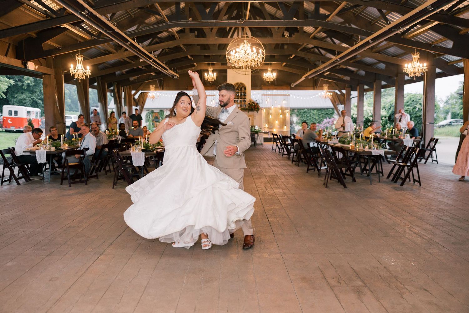 Rustic barn wedding reception venue with wooden beams and elegant chandeliers.