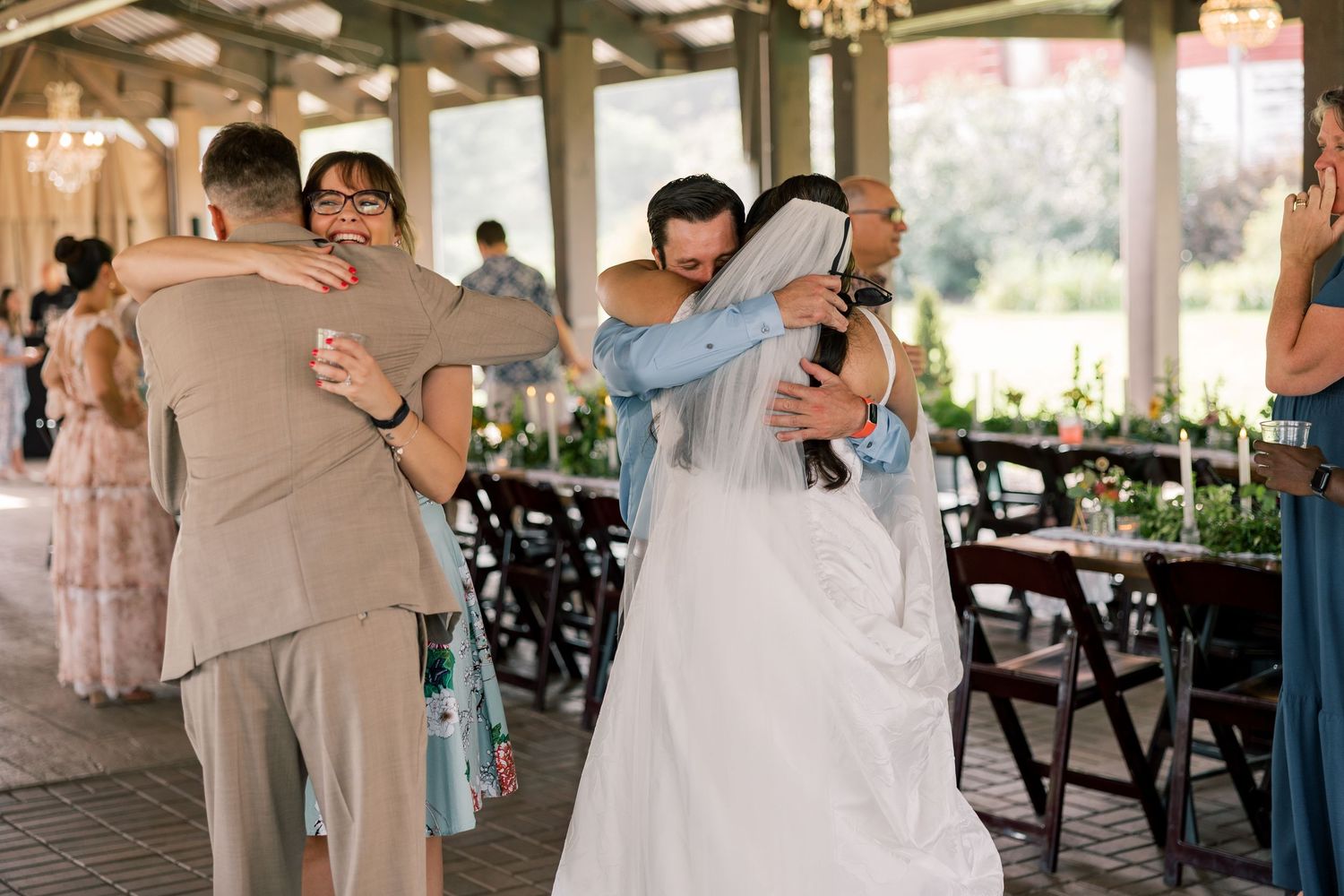 Wedding celebration inside rustic venue with wooden beams and chandeliers.