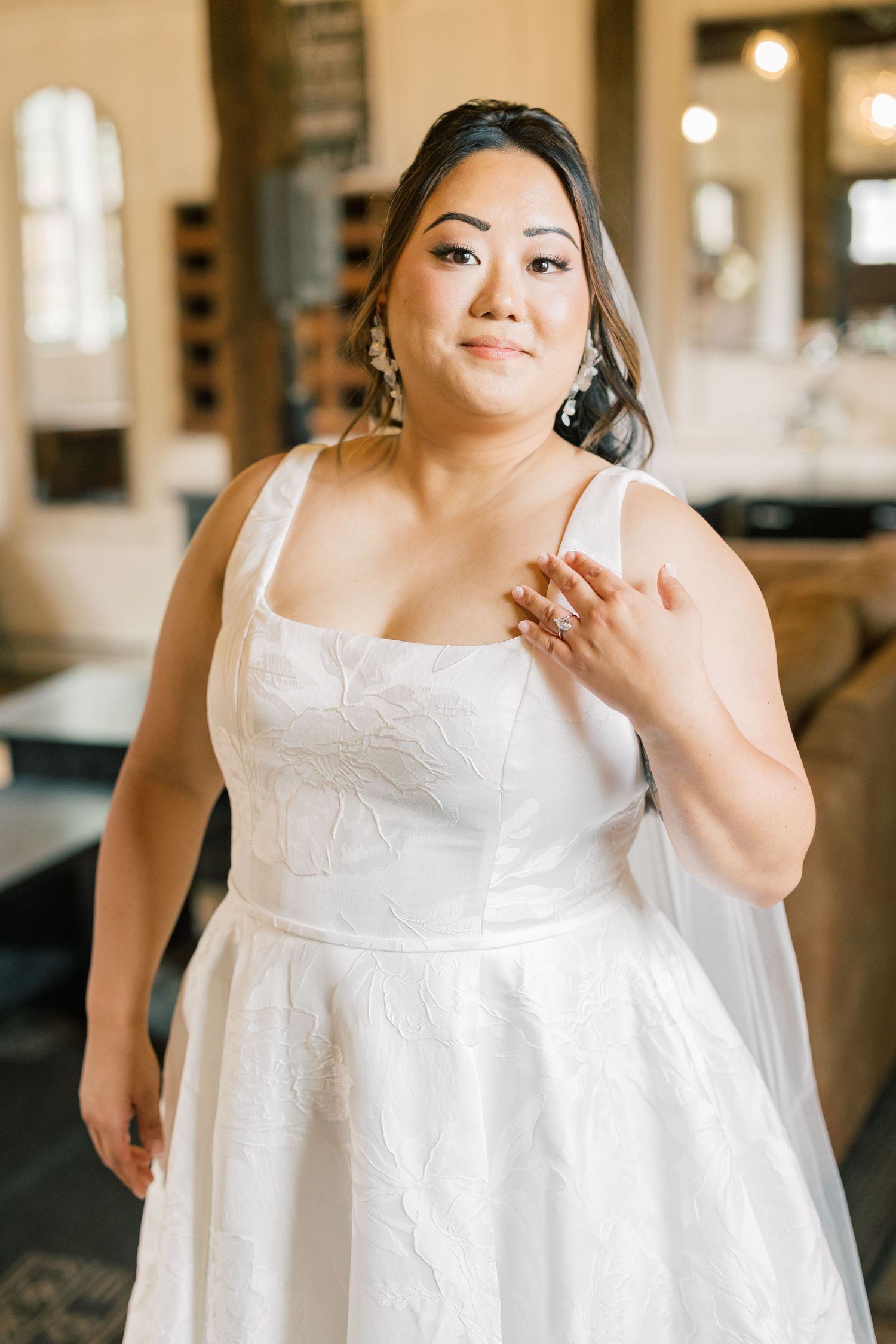 A wedding dress detail showcasing intricate white lace and embroidery in natural lighting.
