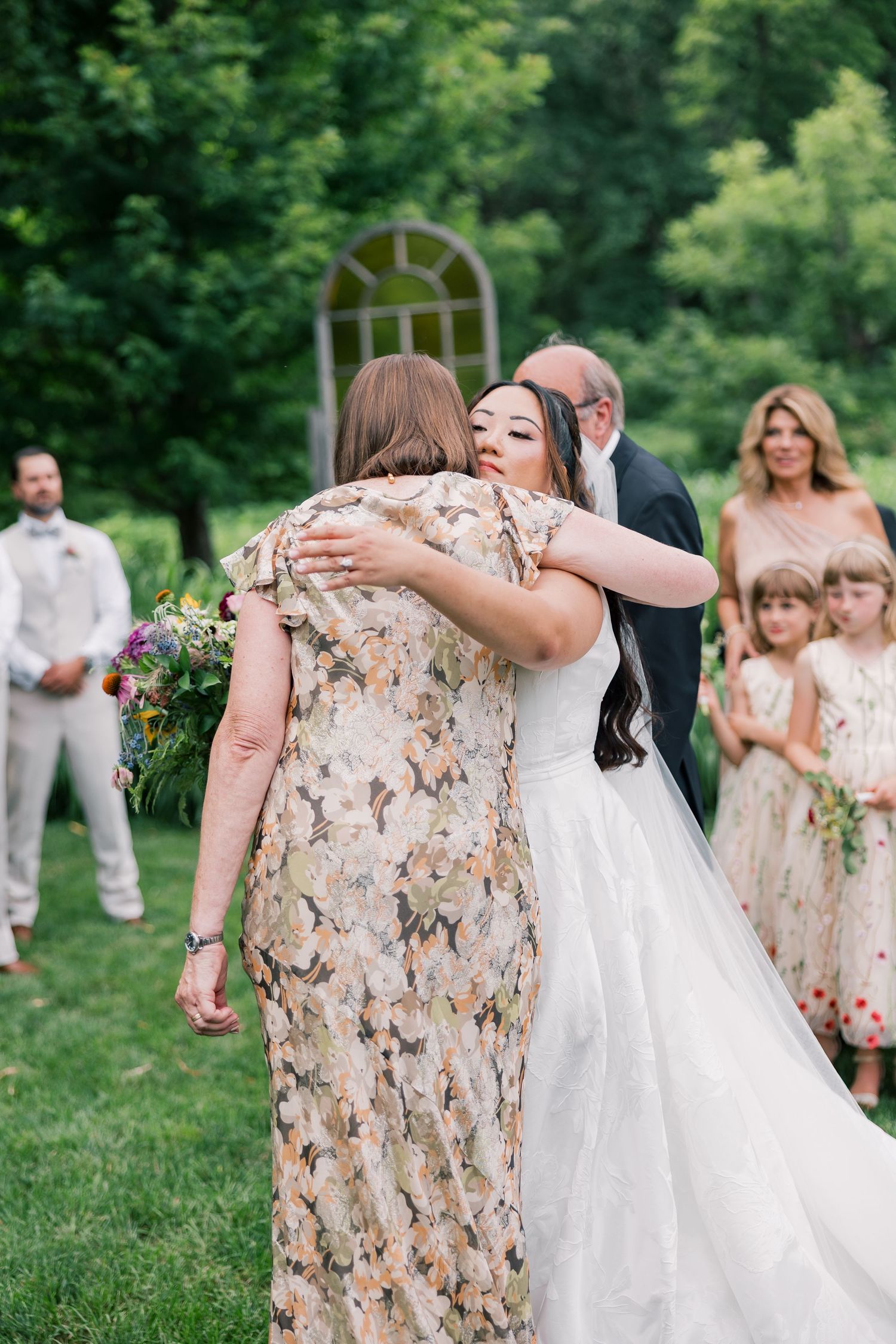 Wedding celebration moments captured on a green lawn with guests in floral dresses.