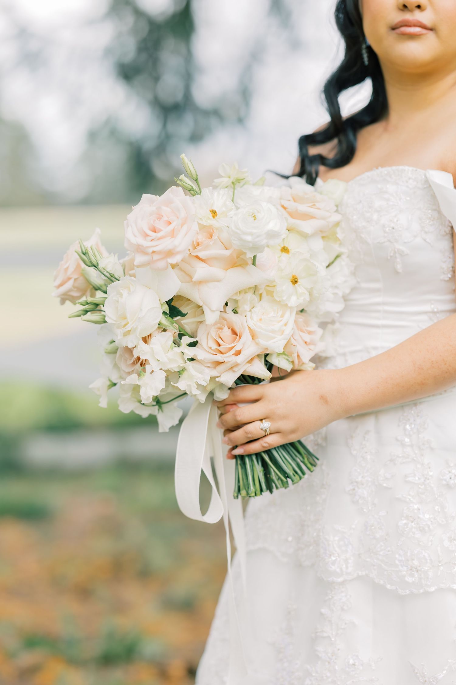 A romantic bridal bouquet of blush and white roses with flowing ribbon.