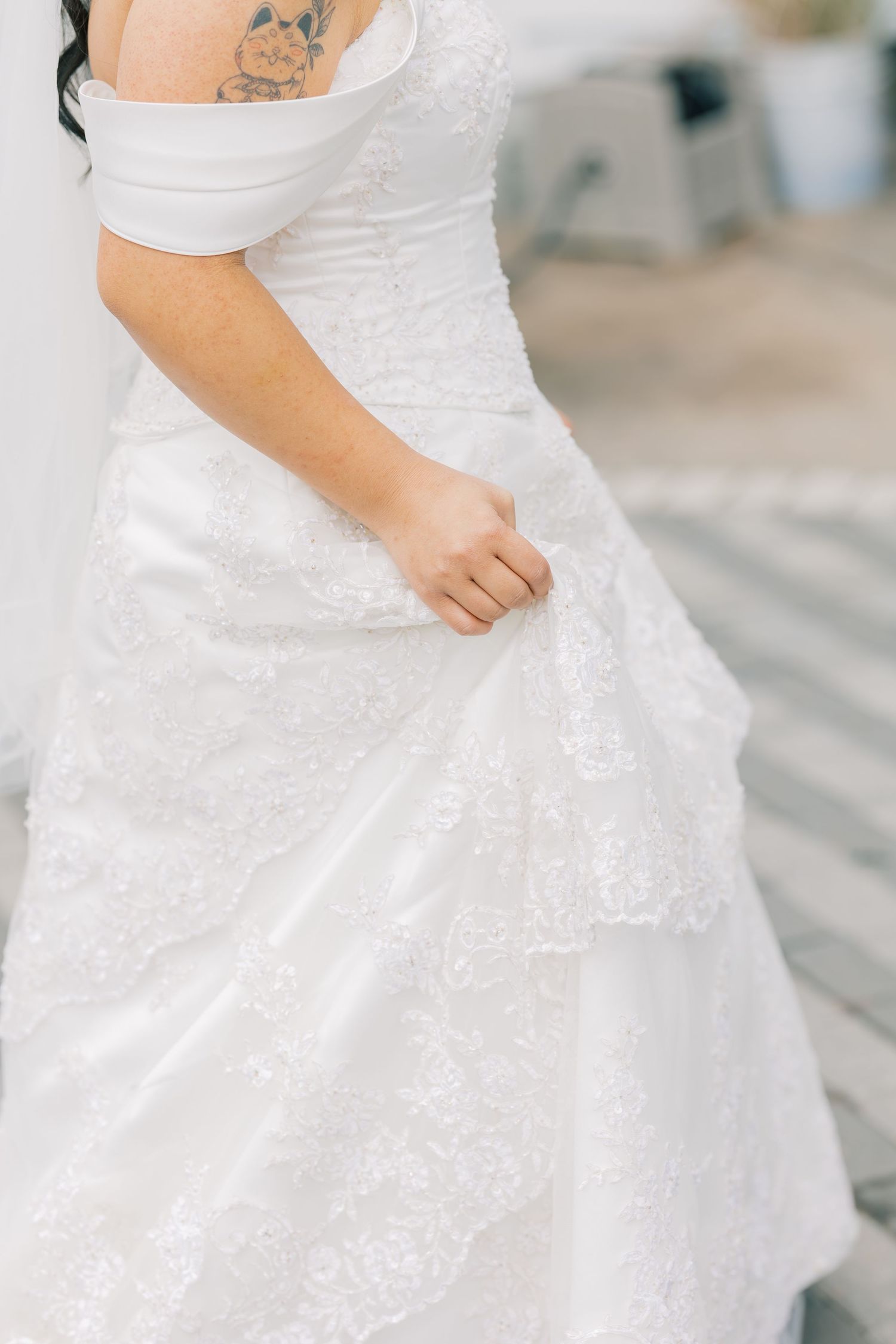 Close-up details of a white lace wedding dress with delicate embroidery and flowing fabric.