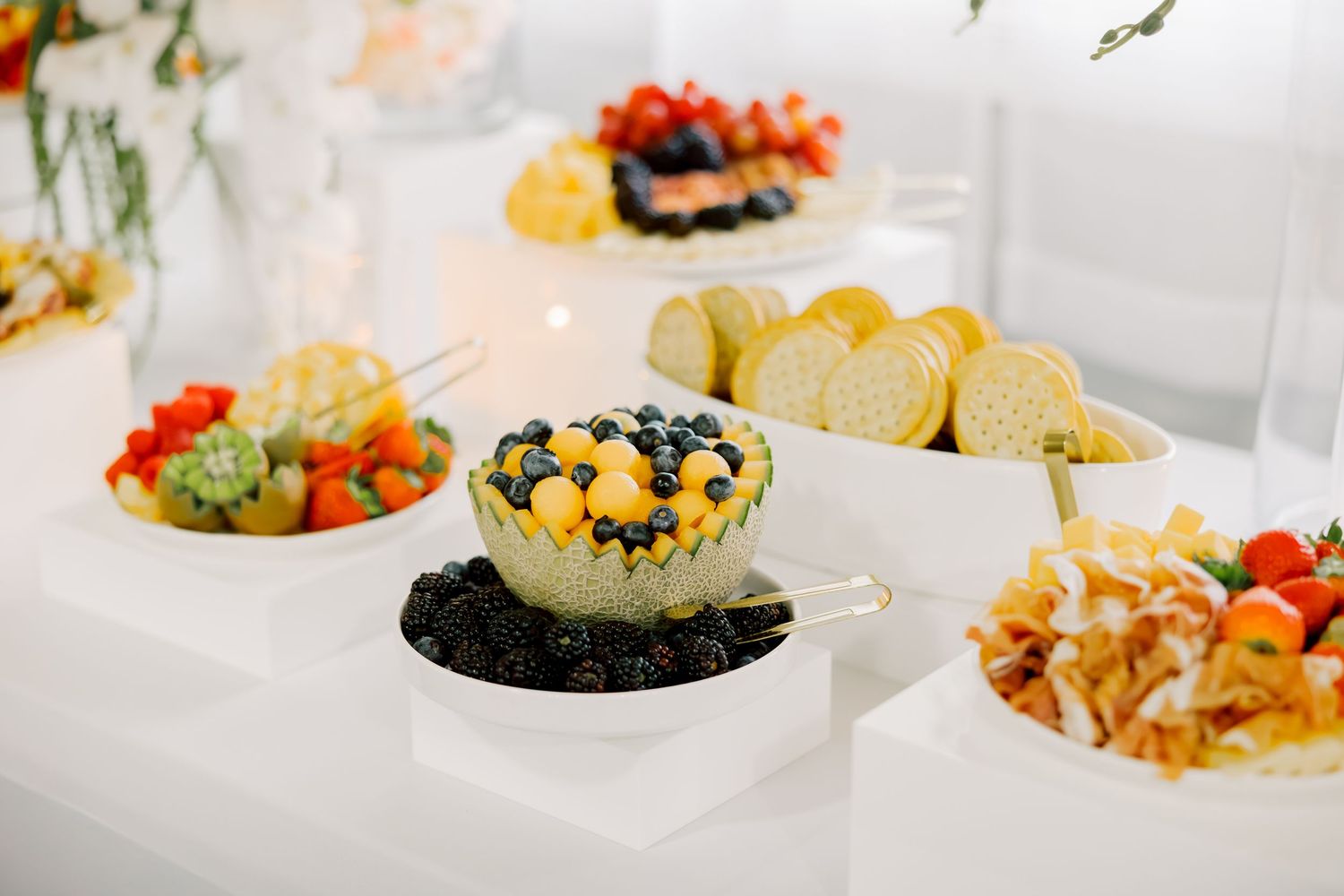 A colorful assortment of appetizers and finger foods arranged in small plates and bowls on a white surface.