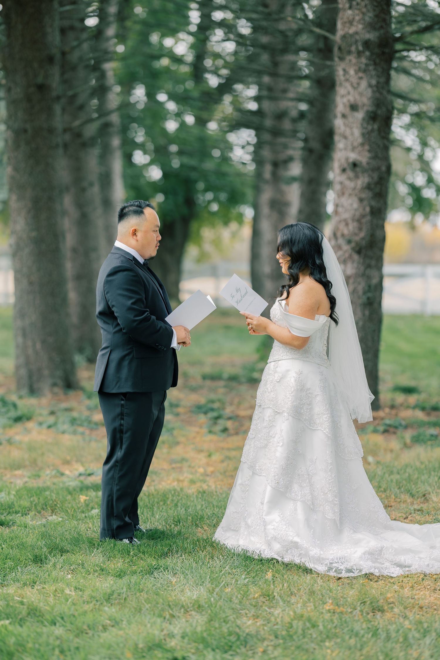 A couple shares a private first look moment in a wooded outdoor setting during their wedding day.