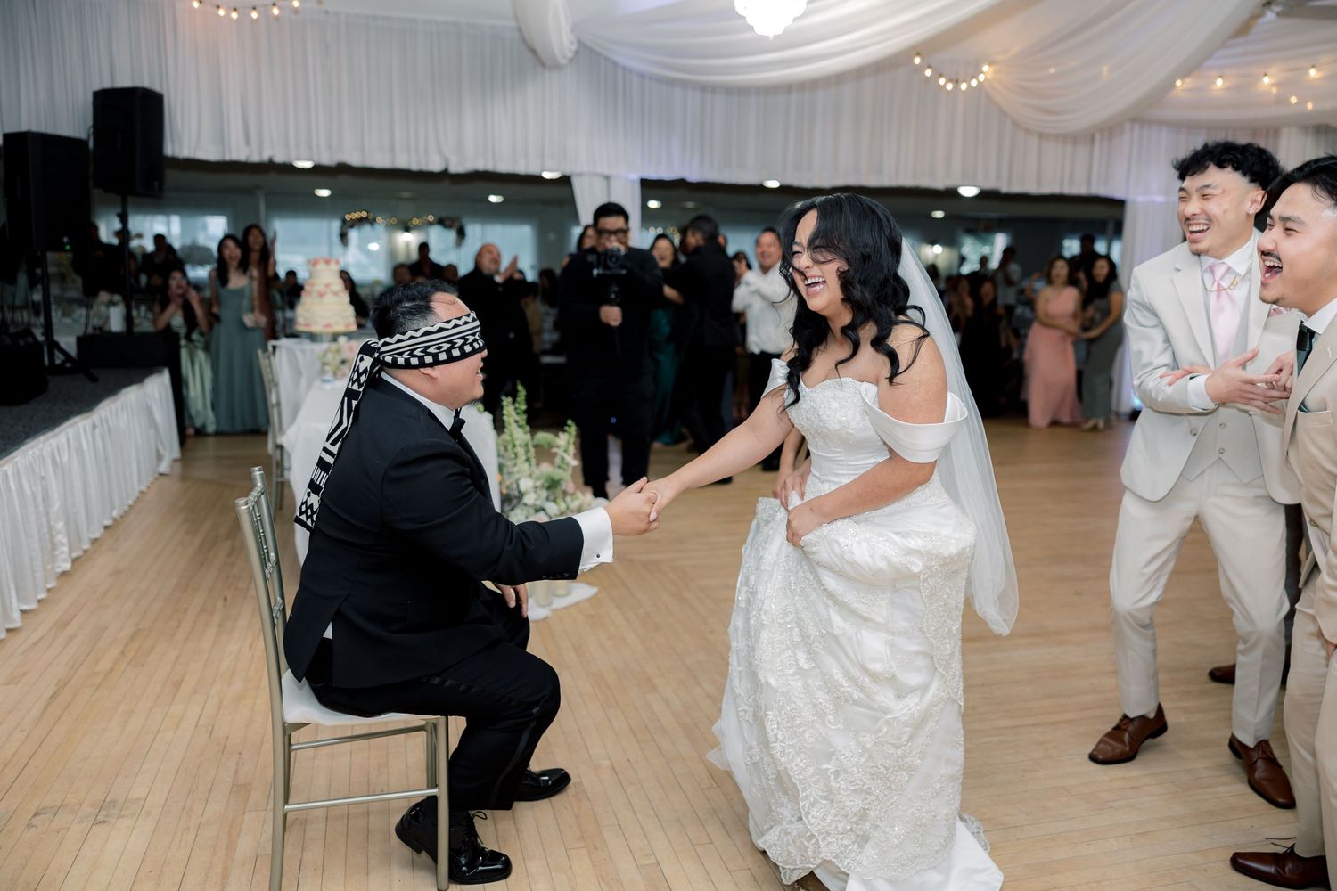 A garter toss tradition at a wedding reception with guests gathered around on a dance floor.