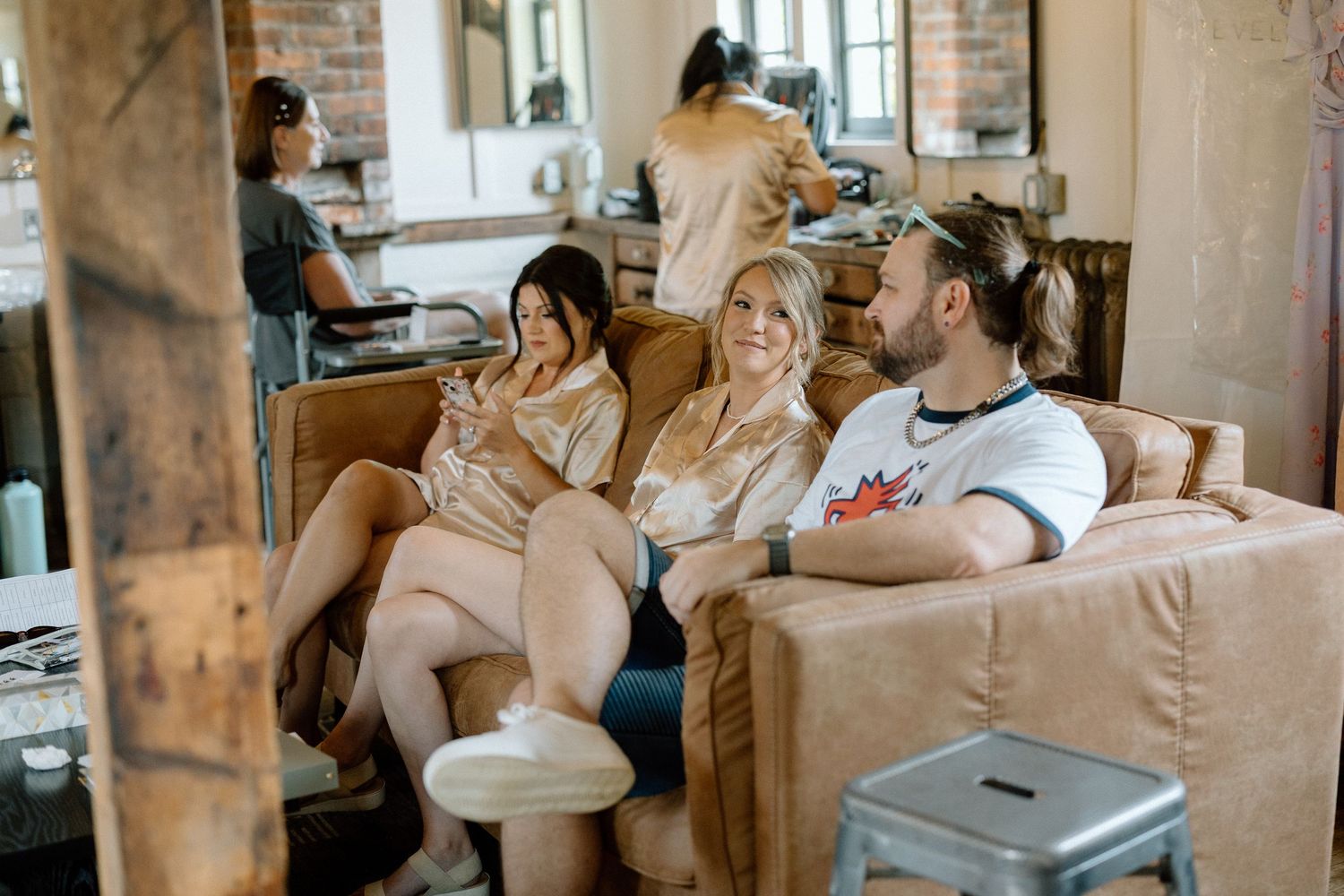 People relaxing in a casual lounge setting with exposed brick walls and comfortable seating.