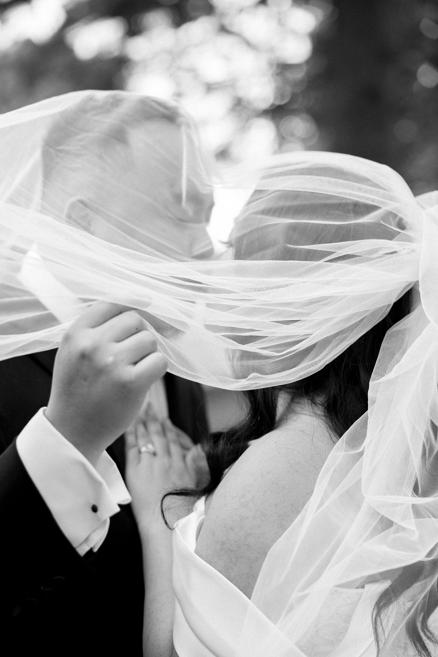 Black and white artistic photo of flowing wedding veil fabric creating ethereal movement.