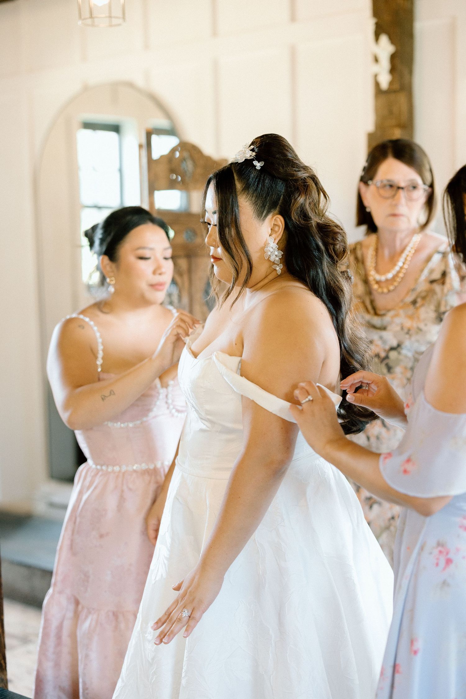 A series of candid moments showing bridesmaids in pink dresses helping with wedding preparations.