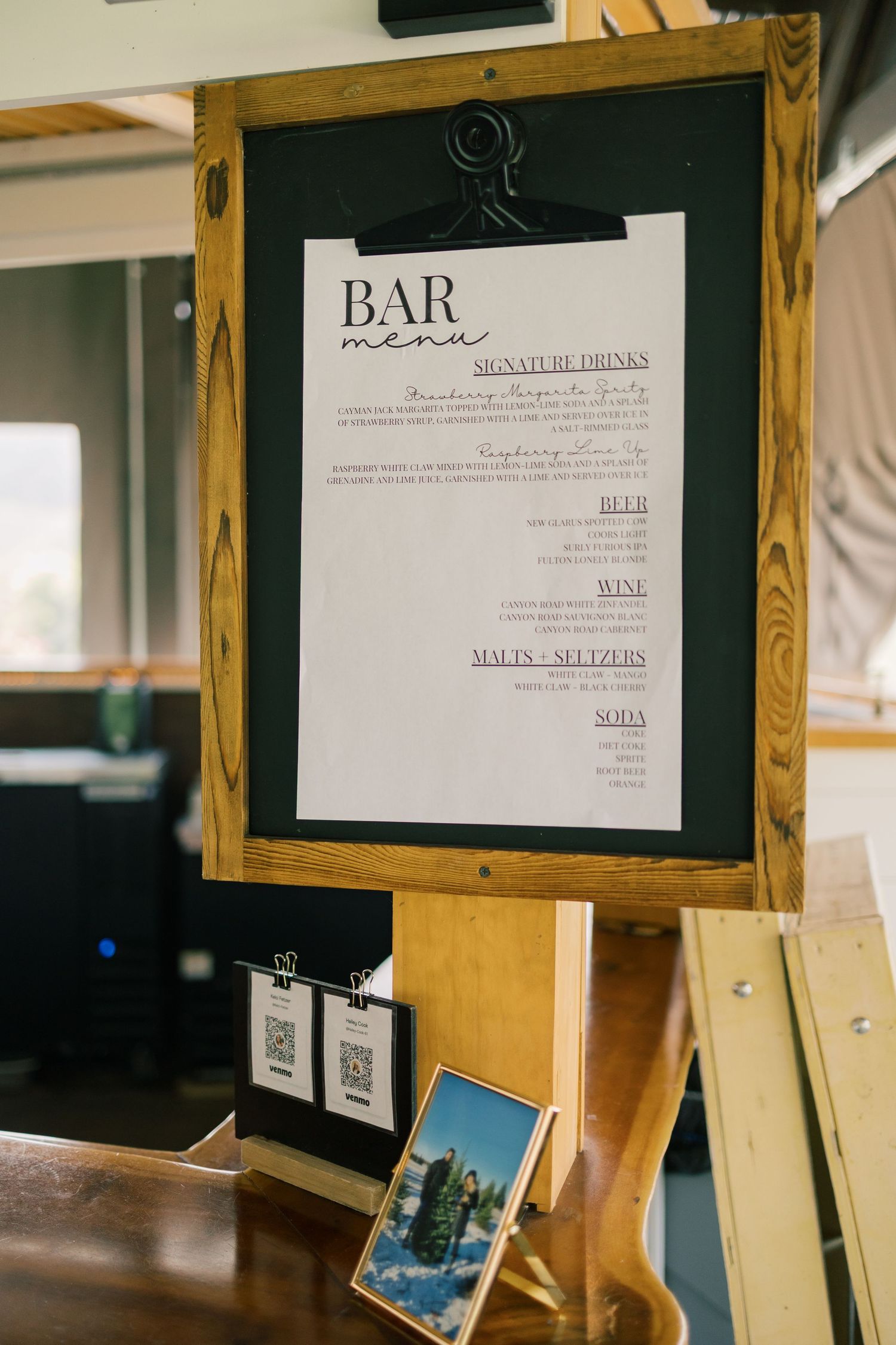 Wedding menu and bar signs displayed in wooden frames at reception.