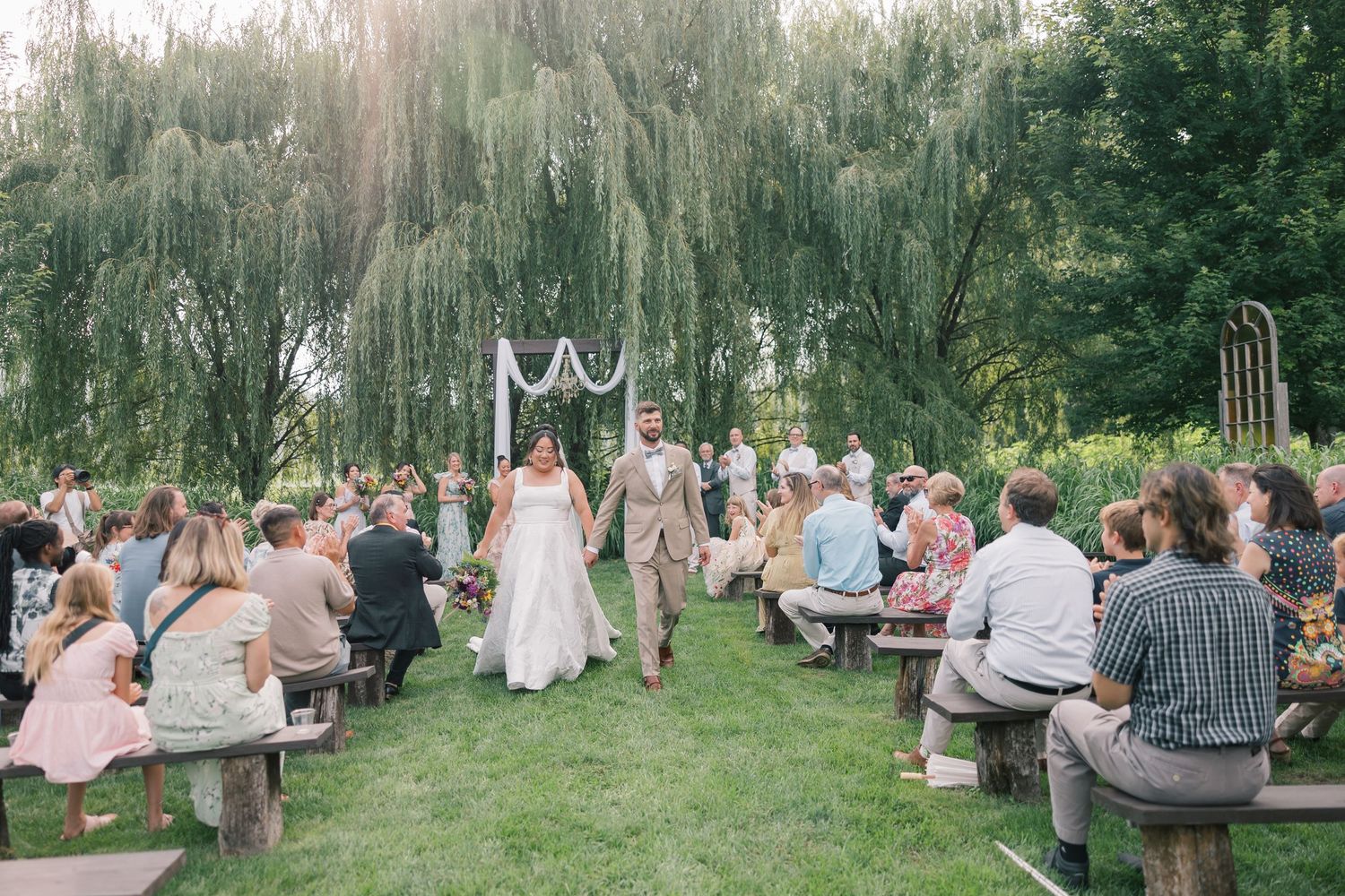 Panoramic view of wedding guests gathered on a grassy lawn for an outdoor celebration.