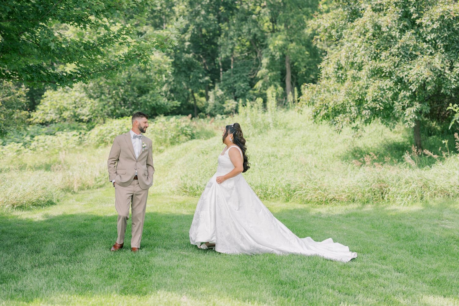 A couple shares a romantic moment on a lush green lawn during their wedding day.