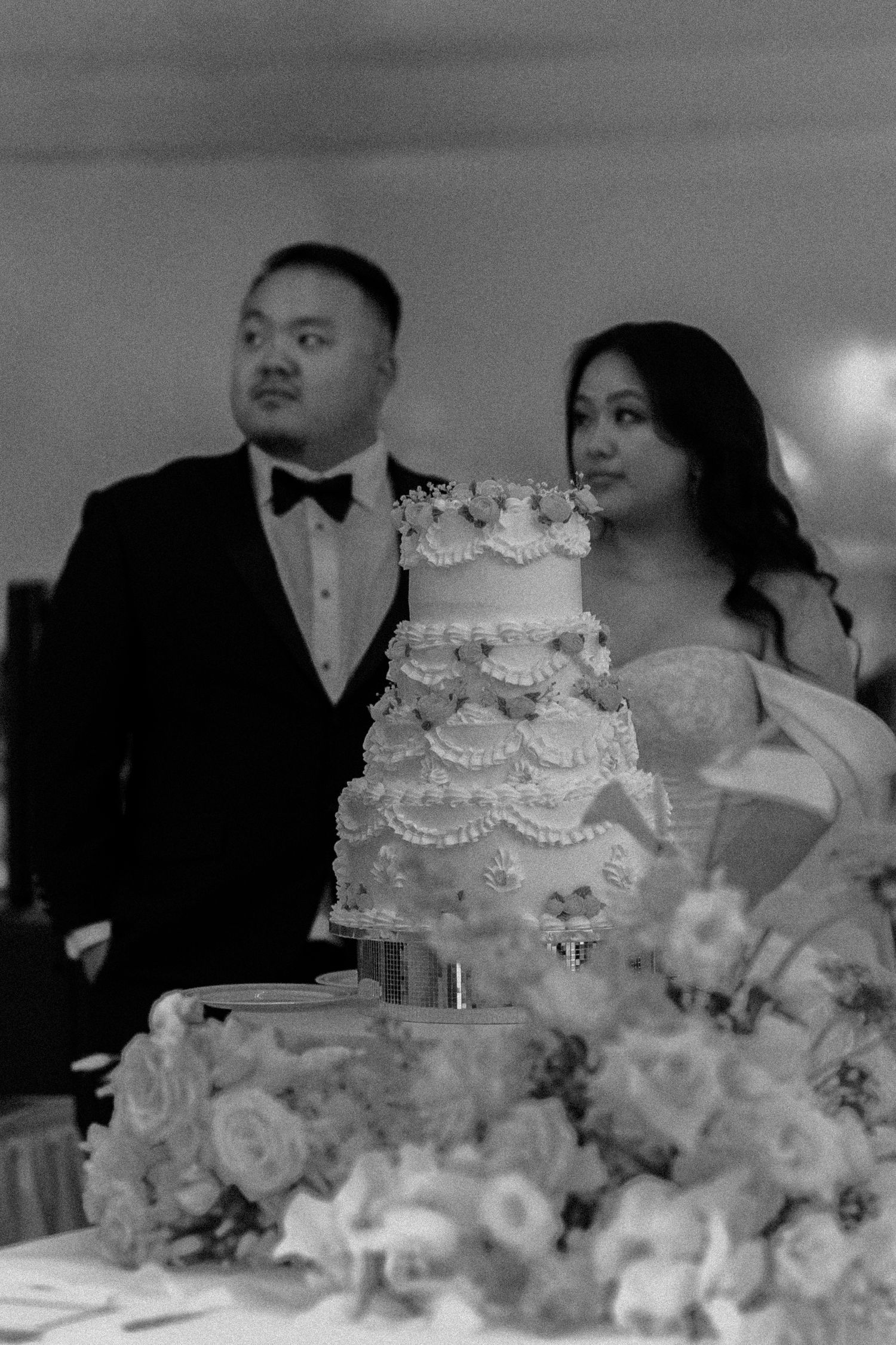 Elegant white wedding cake decorated with floral arrangements at a reception.
