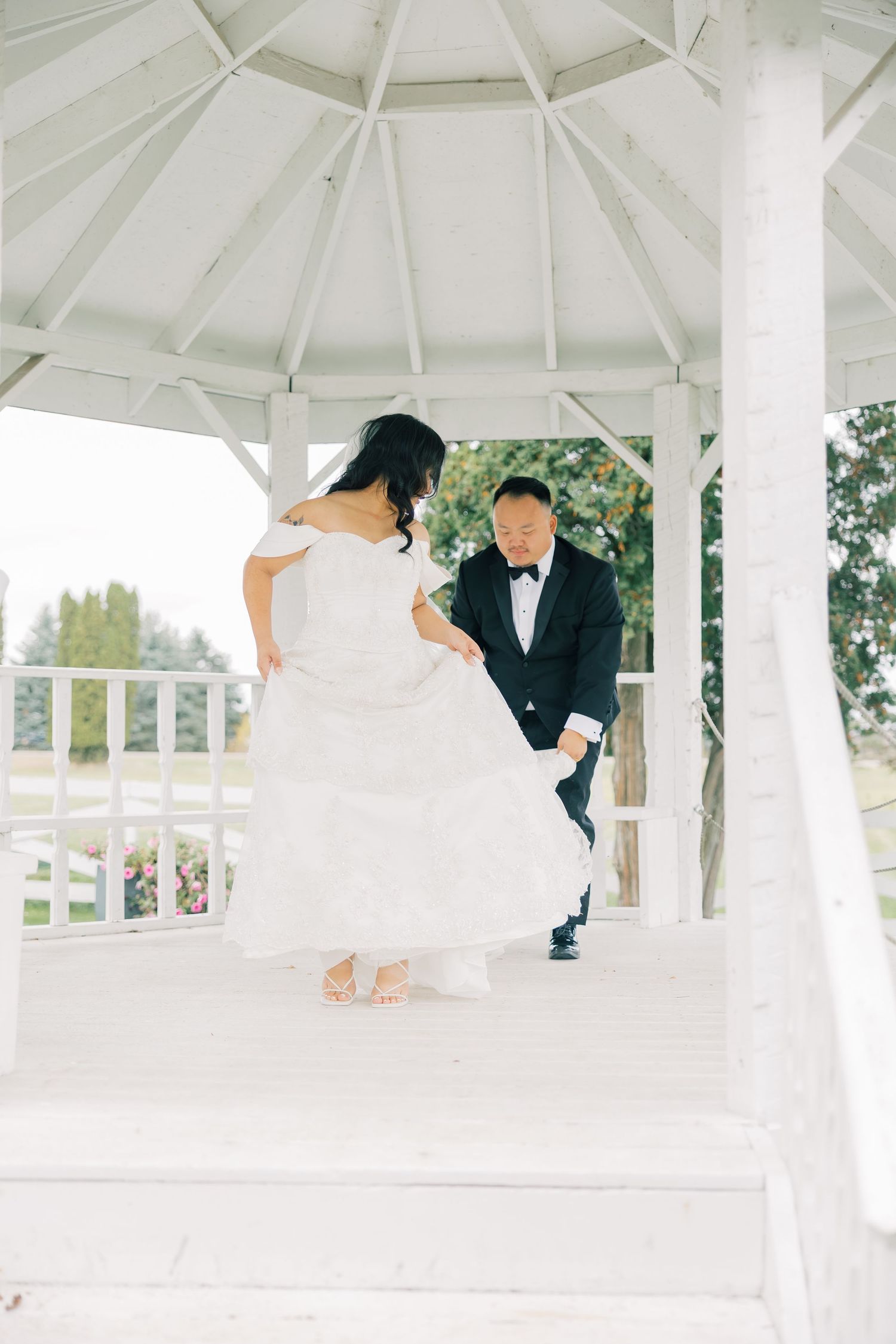 Newlyweds dancing and twirling in an elegant white gazebo during their wedding celebration.