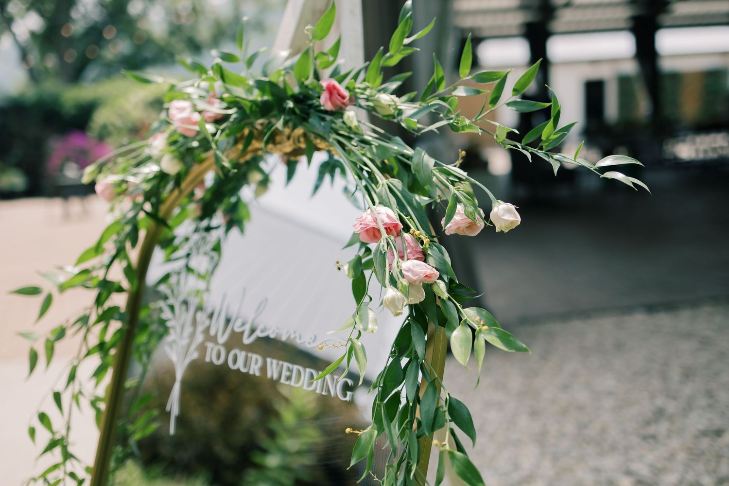 A white piano decorated with an elegant floral garland featuring pink roses and green foliage.