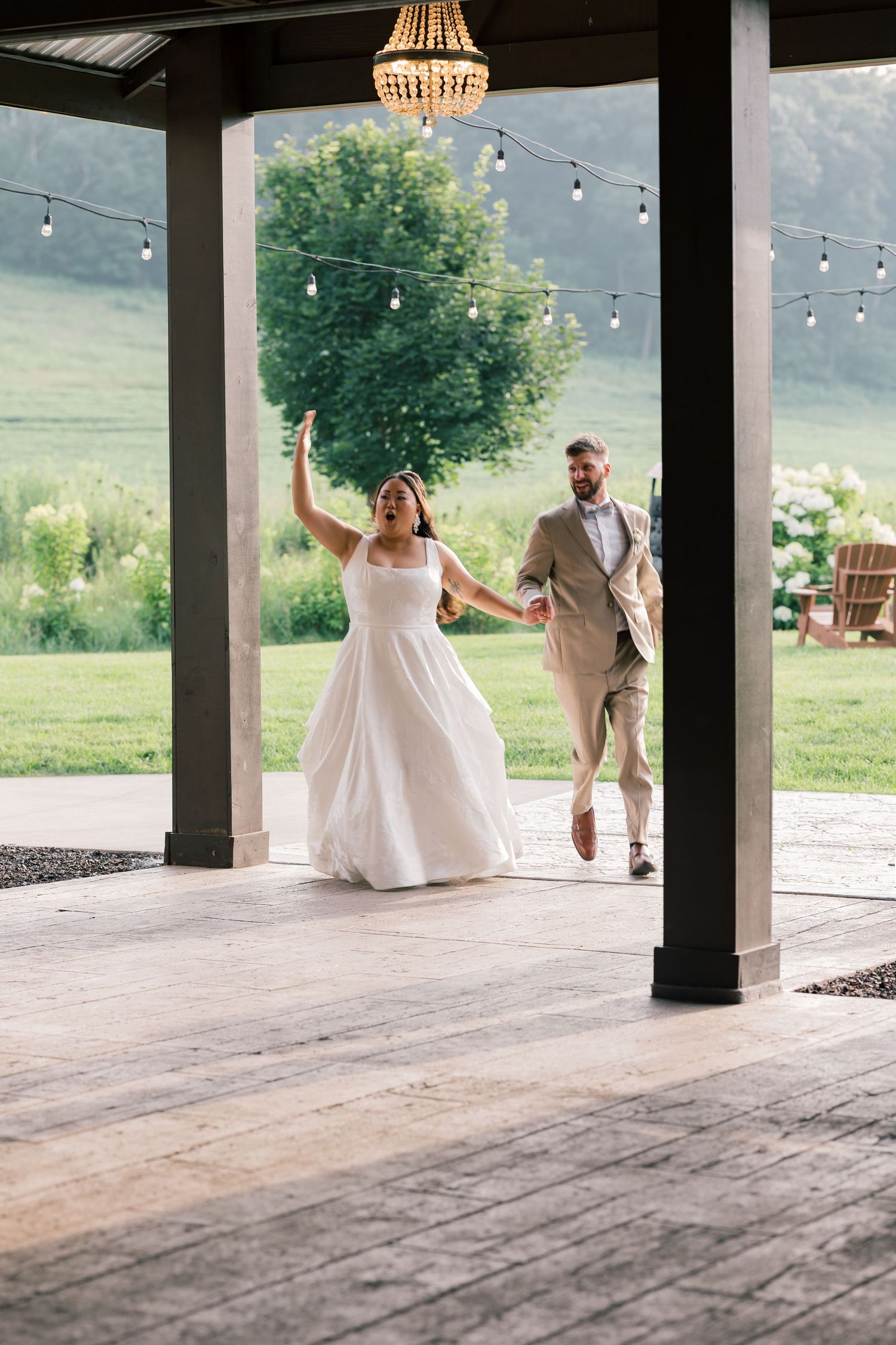 Couple dances under string lights on covered porch with rustic wood flooring.