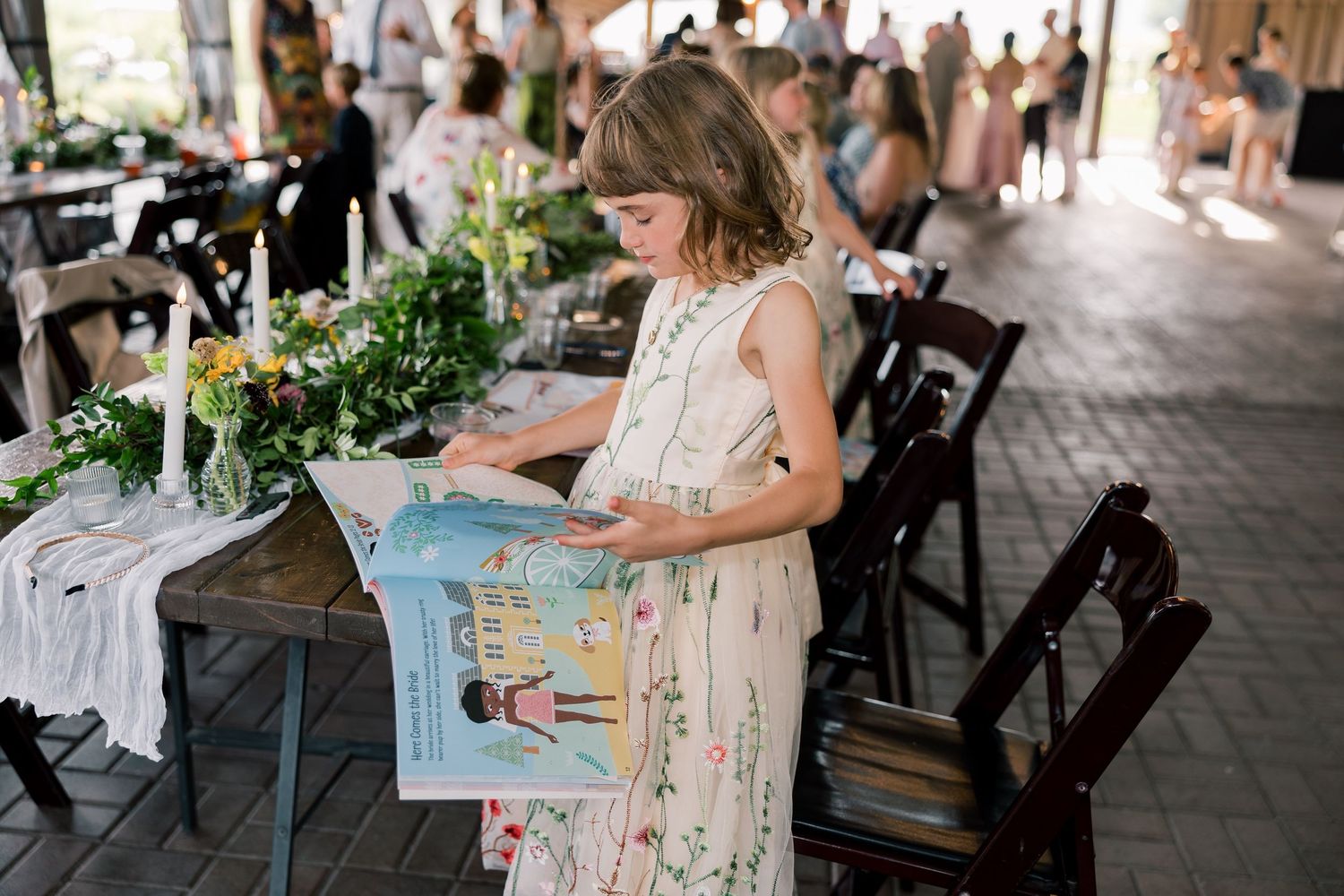 Wedding reception guests seated at tables under covered outdoor venue.