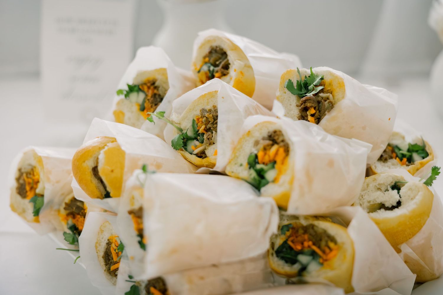 Fresh spring rolls filled with vibrant vegetables and herbs arranged in a row on a white surface.